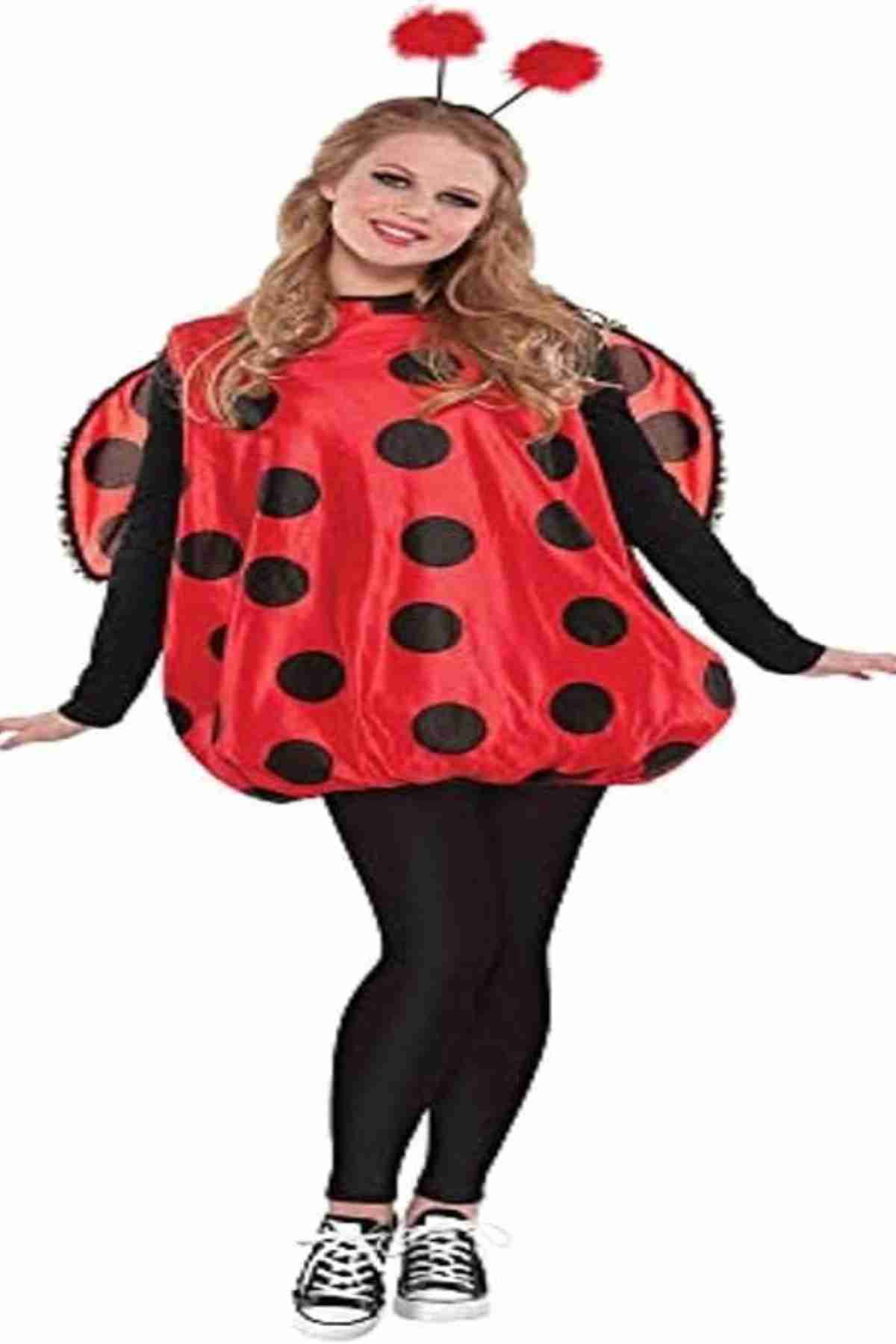 Person wearing a red ladybug costume with black spots, black leggings, sneakers, and a headband with red antennae, standing against a white background.