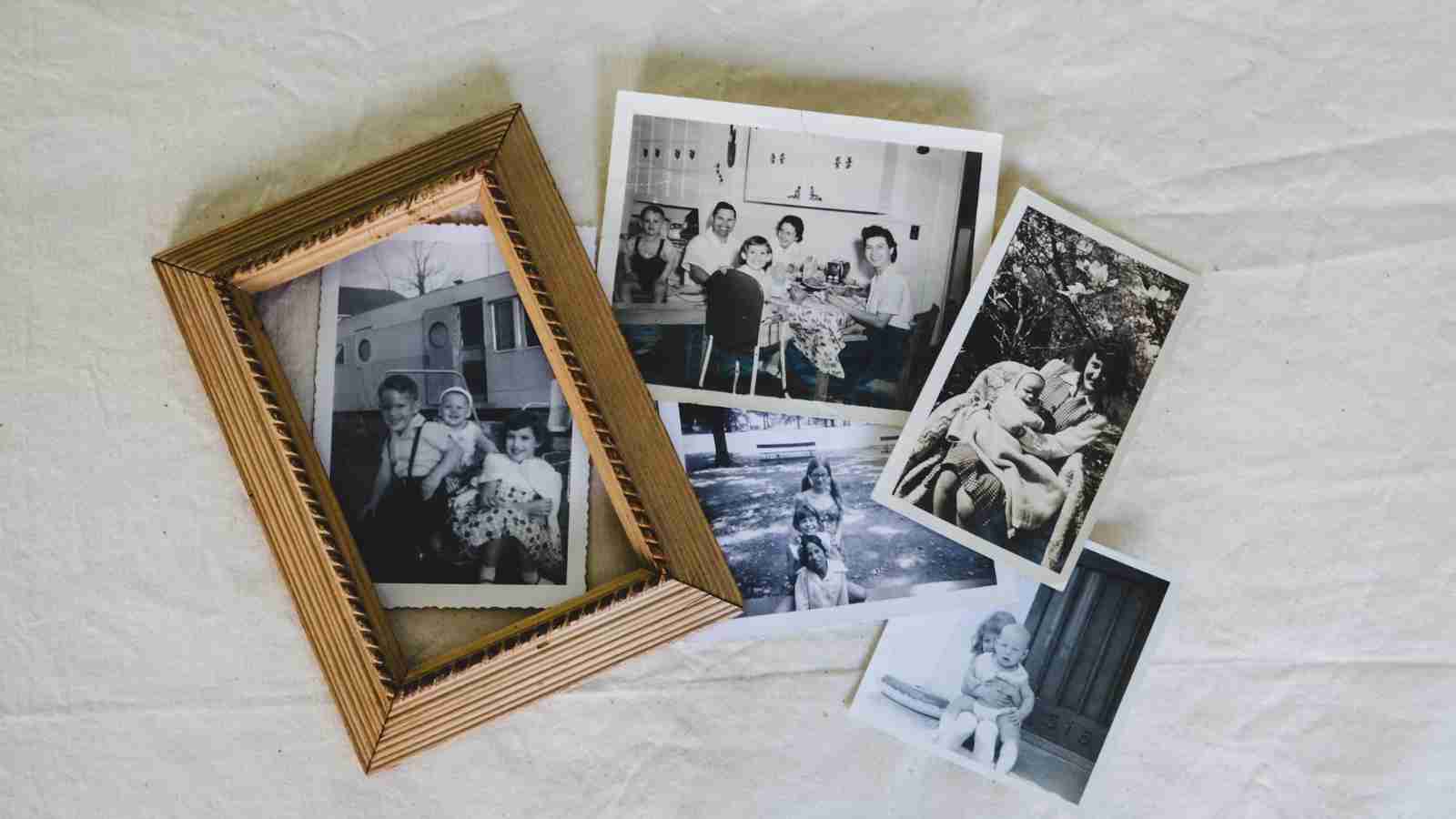 Several black and white family photos are scattered on a light-colored surface, with one photo in a light-colored frame.