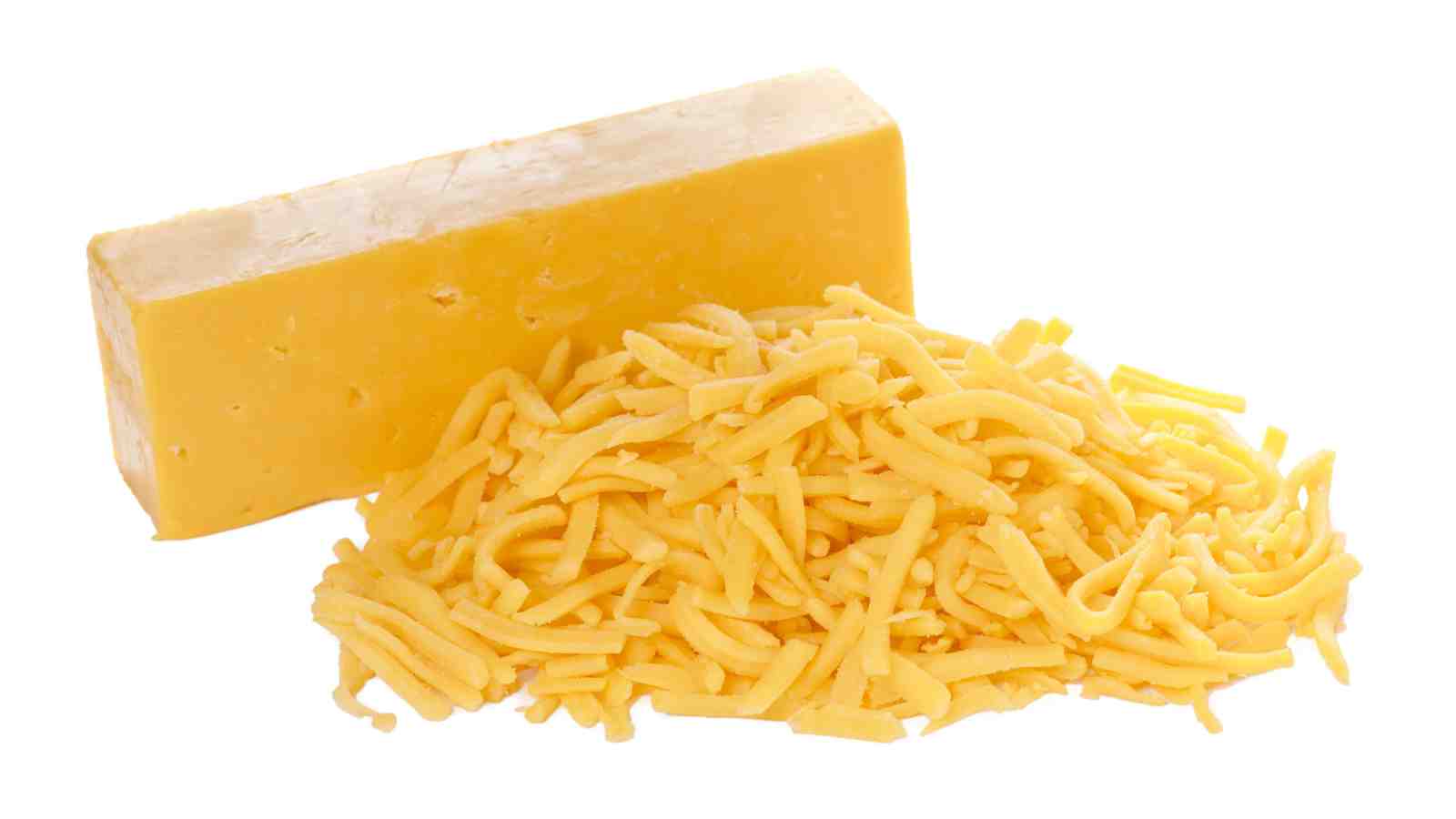 A block of cheddar cheese sits next to a pile of shredded cheddar cheese.