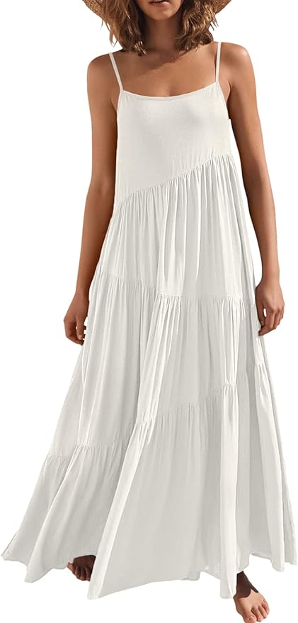 A woman wearing a sleeveless, white, tiered maxi dress with thin straps and a wide-brimmed hat.