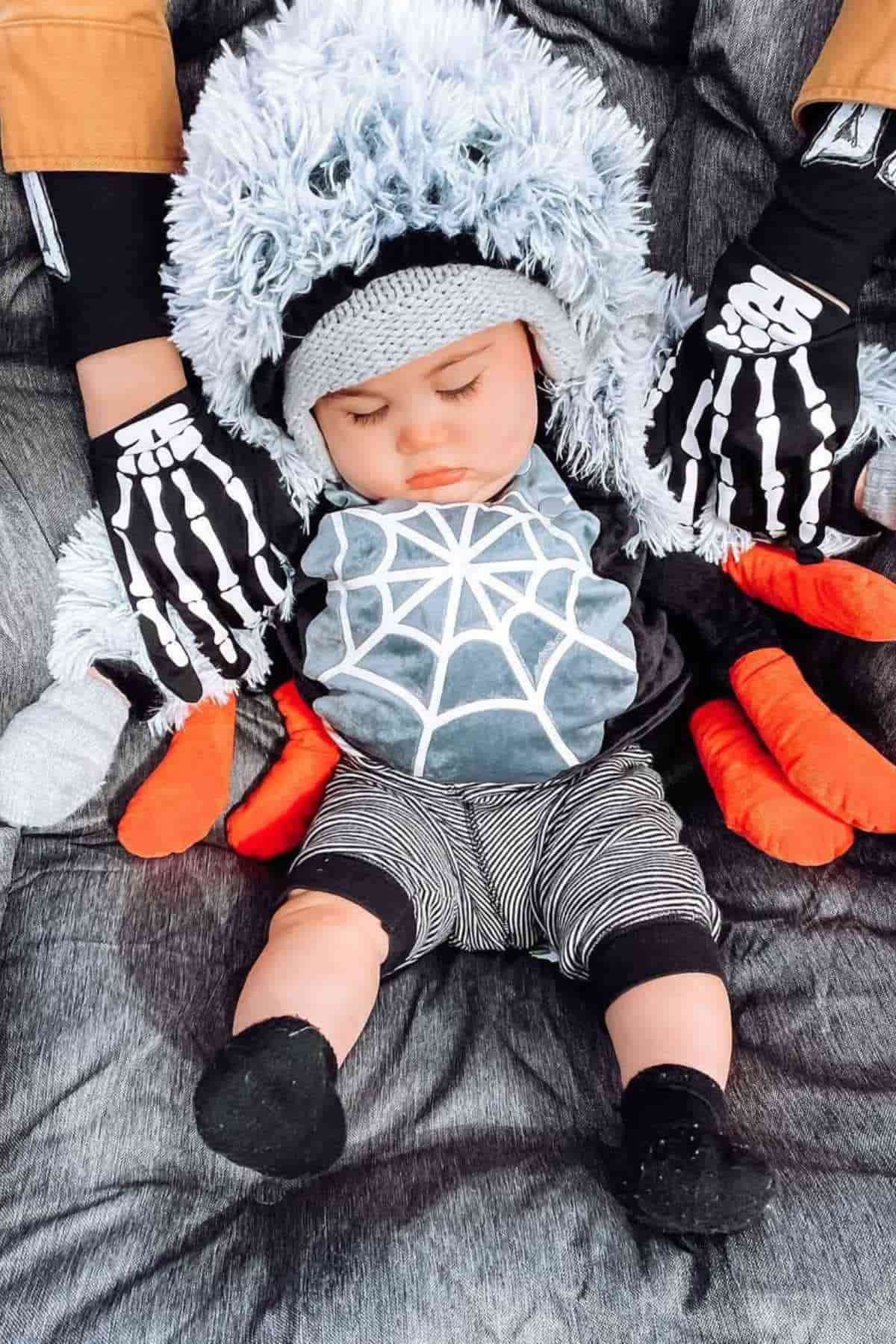 A baby wearing a printed spider  web shirt imitating a spider fox costume.