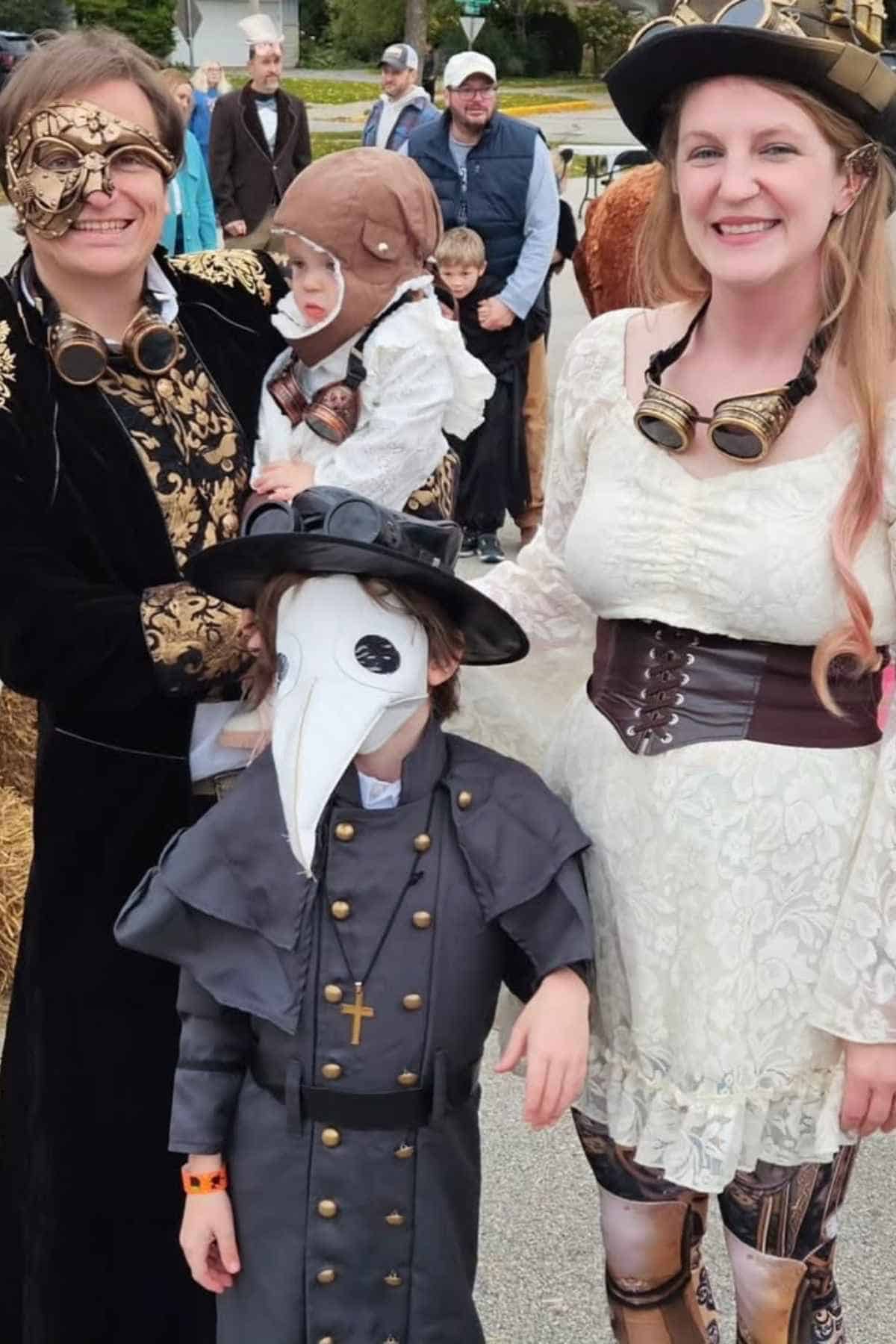 Three people and a child wear detailed steampunk and plague doctor costumes outdoors, with other people visible in the background.