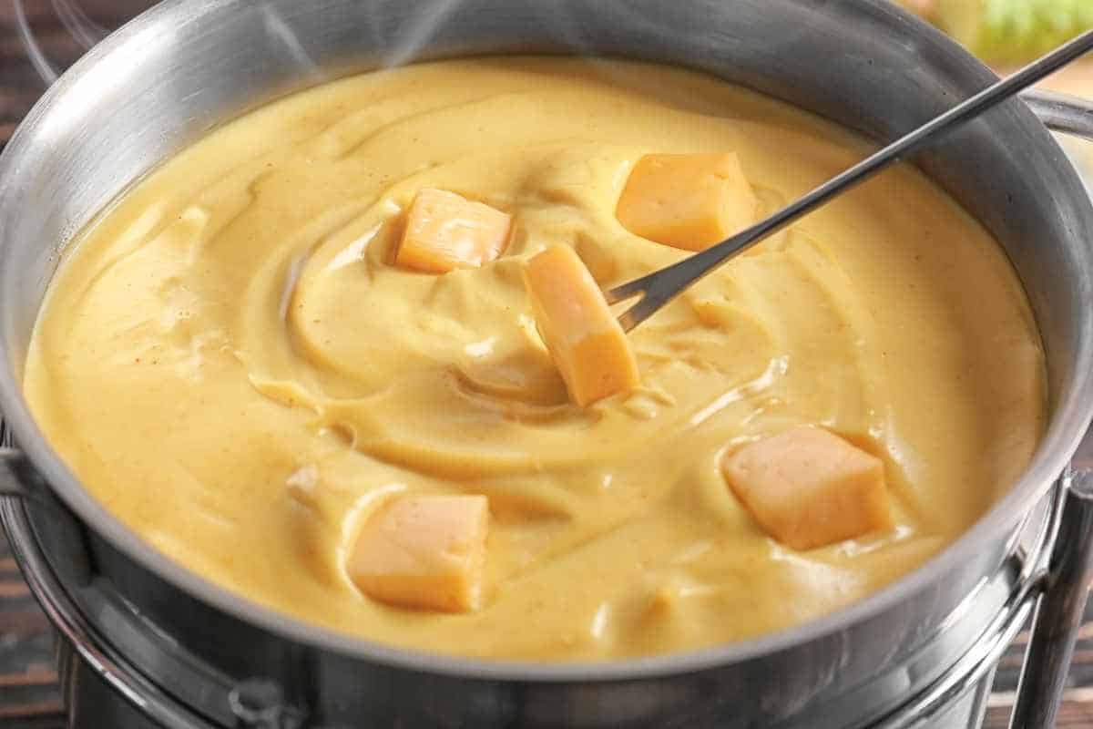 Melting pieces of cheese in a stainless pan.