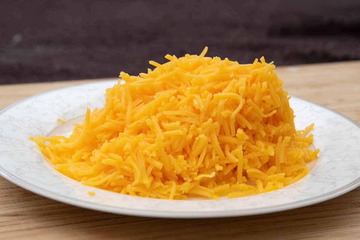 A pre-shredded cheese in a white patterned plate.
