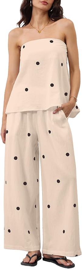 Woman wearing a strapless, loose-fitting cream outfit with black polka dots; wide-leg pants and matching top; black sandals; minimal jewelry.