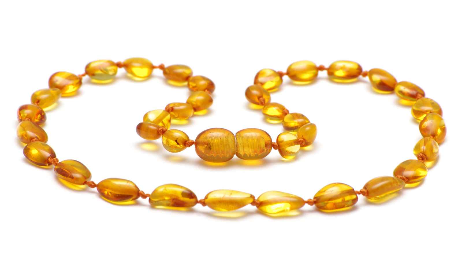 A close-up of a polished amber beaded necklace and bracelet set, arranged in loops on a white background.