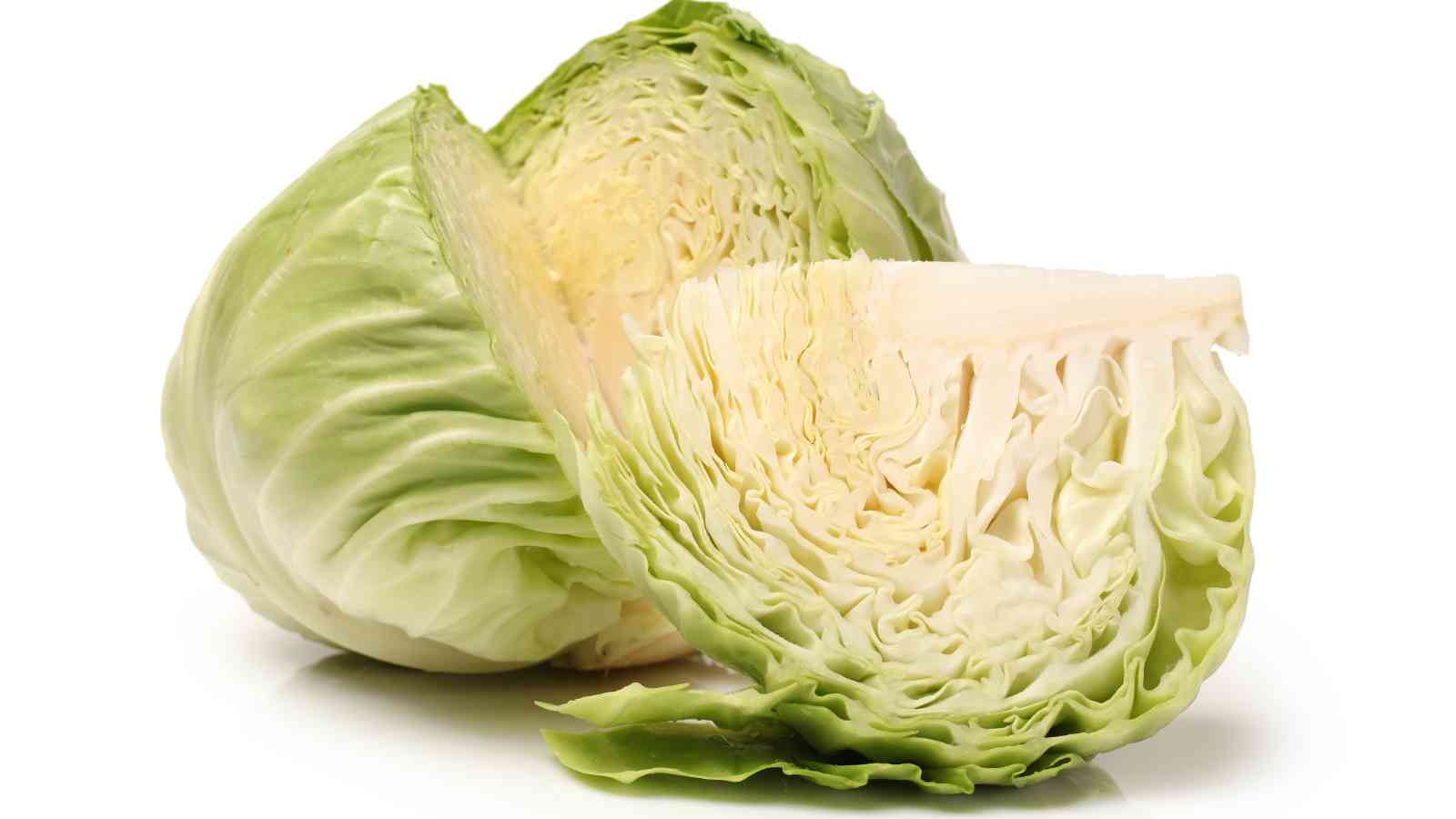 A whole green cabbage with a quarter section cut out, showing the tightly packed leaves and white core, set against a white background.