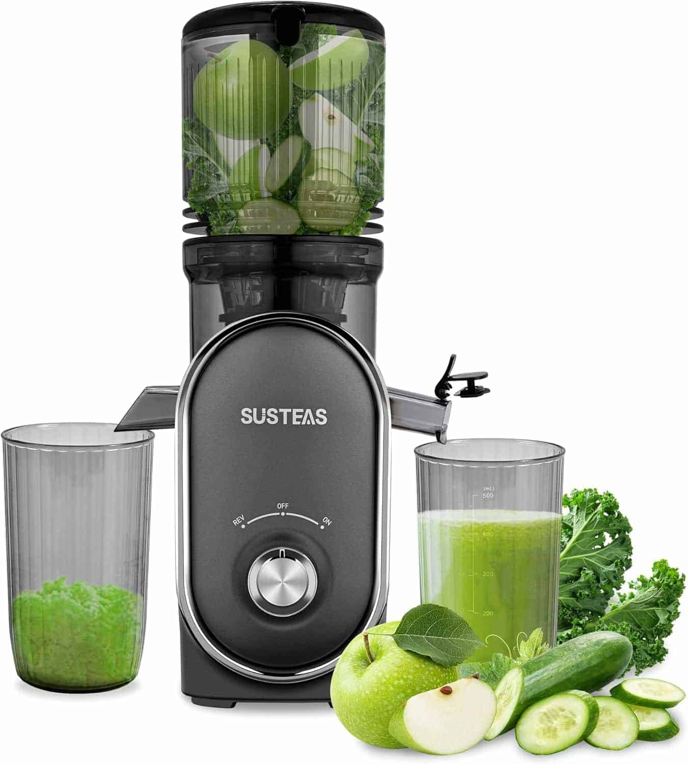 A black Susteas juicer with a dial is shown with green fruits and vegetables inside and around it, including apple, cucumber, kale, and two glasses, one filled with juice and one with pulp.