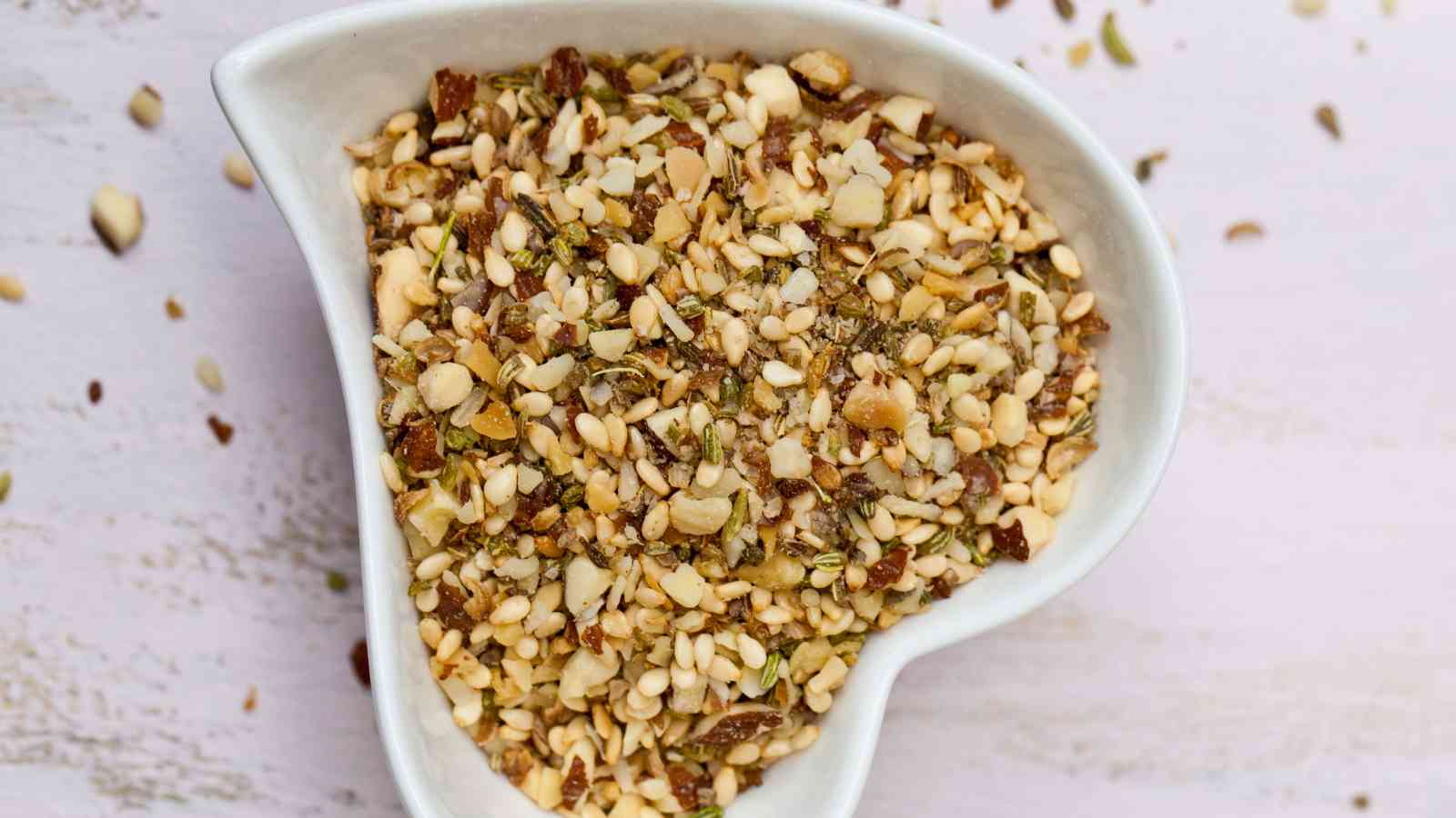 A white, heart-shaped bowl filled with dukkah.