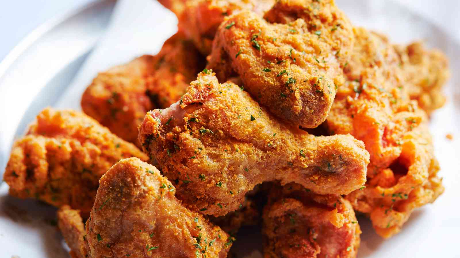 A plate of golden-brown fried chicken pieces garnished with herbs.