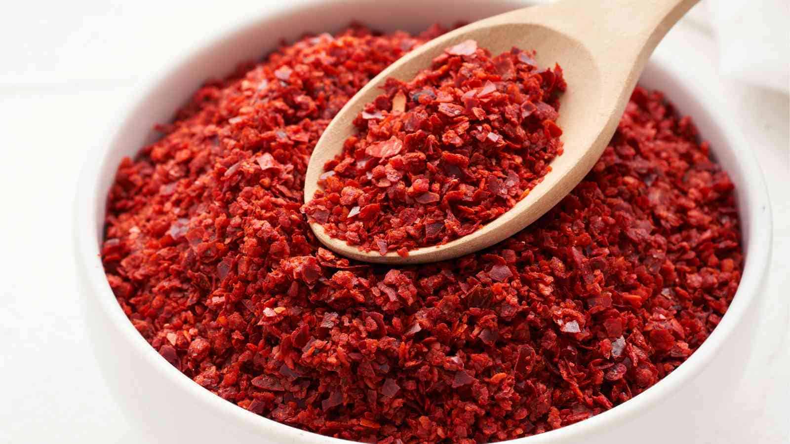 A wooden spoon rests on a bowl filled with gochugaru.