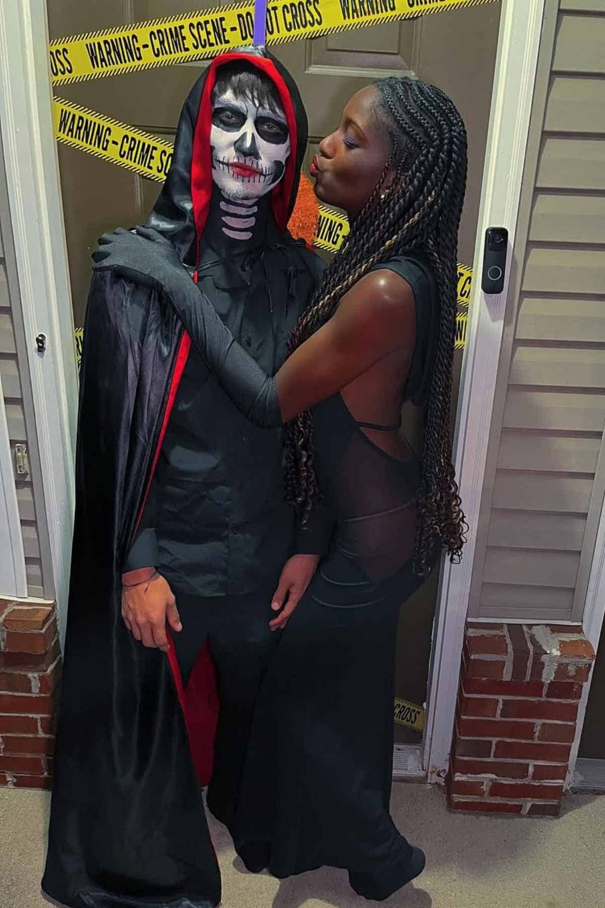 A man and woman dressed in black and red costumes, recreating Grim and Malaria character.