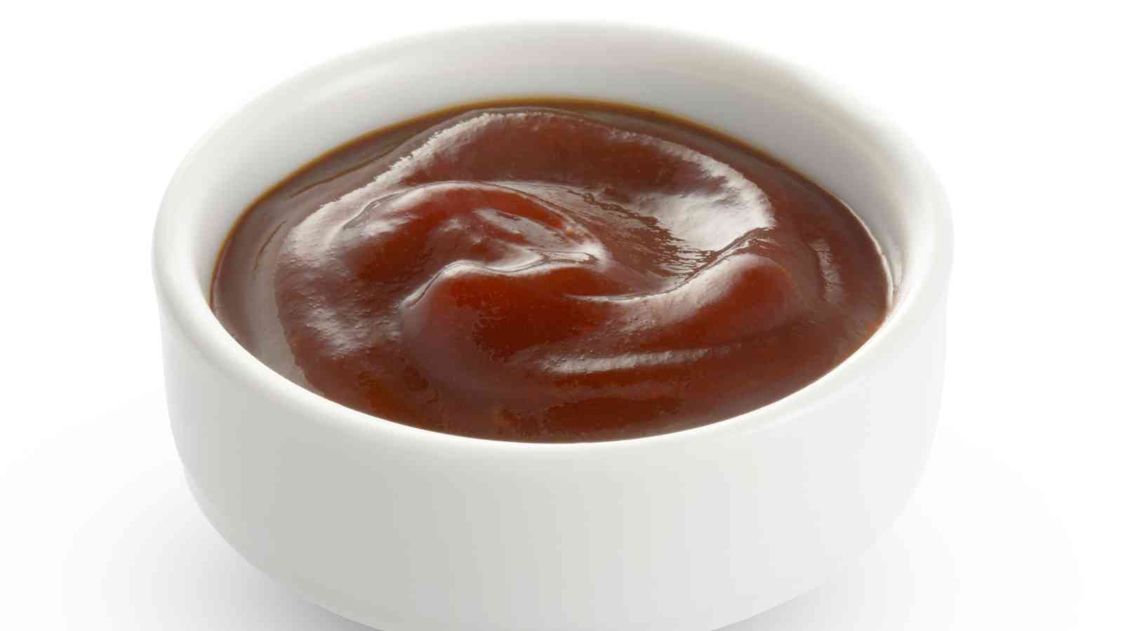 A small white bowl filled with hoisin sauce on a plain white background.