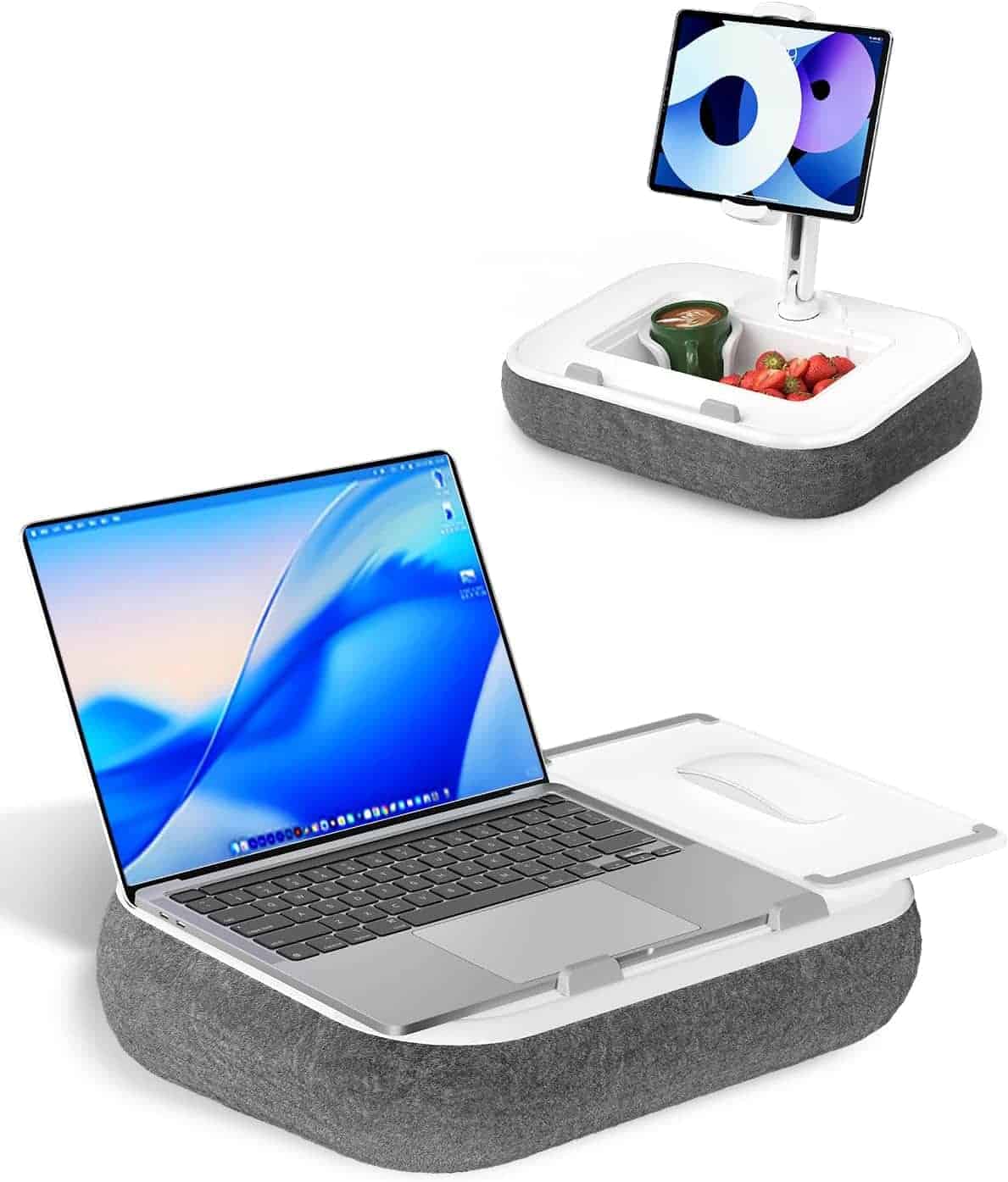 A cushioned lap desk with a laptop, a side compartment holding a cup and strawberries, and a raised slot supporting a tablet.