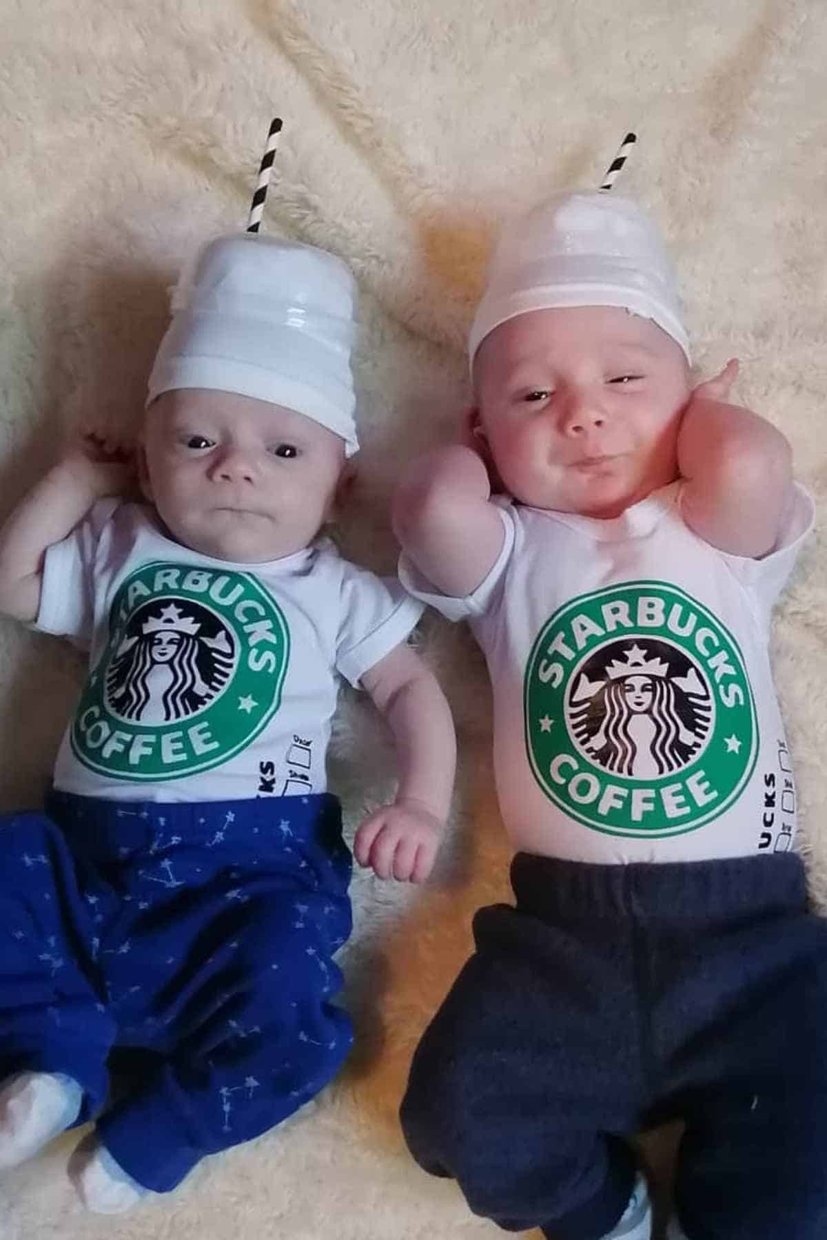 Two babies lie on a soft surface wearing white hats resembling Starbucks cup lids and onesies with the Starbucks Coffee logo.