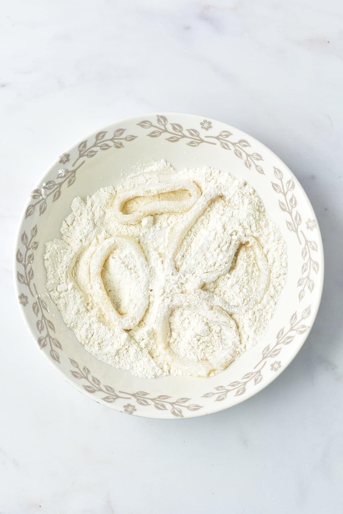 Coating calamari rings in flour.