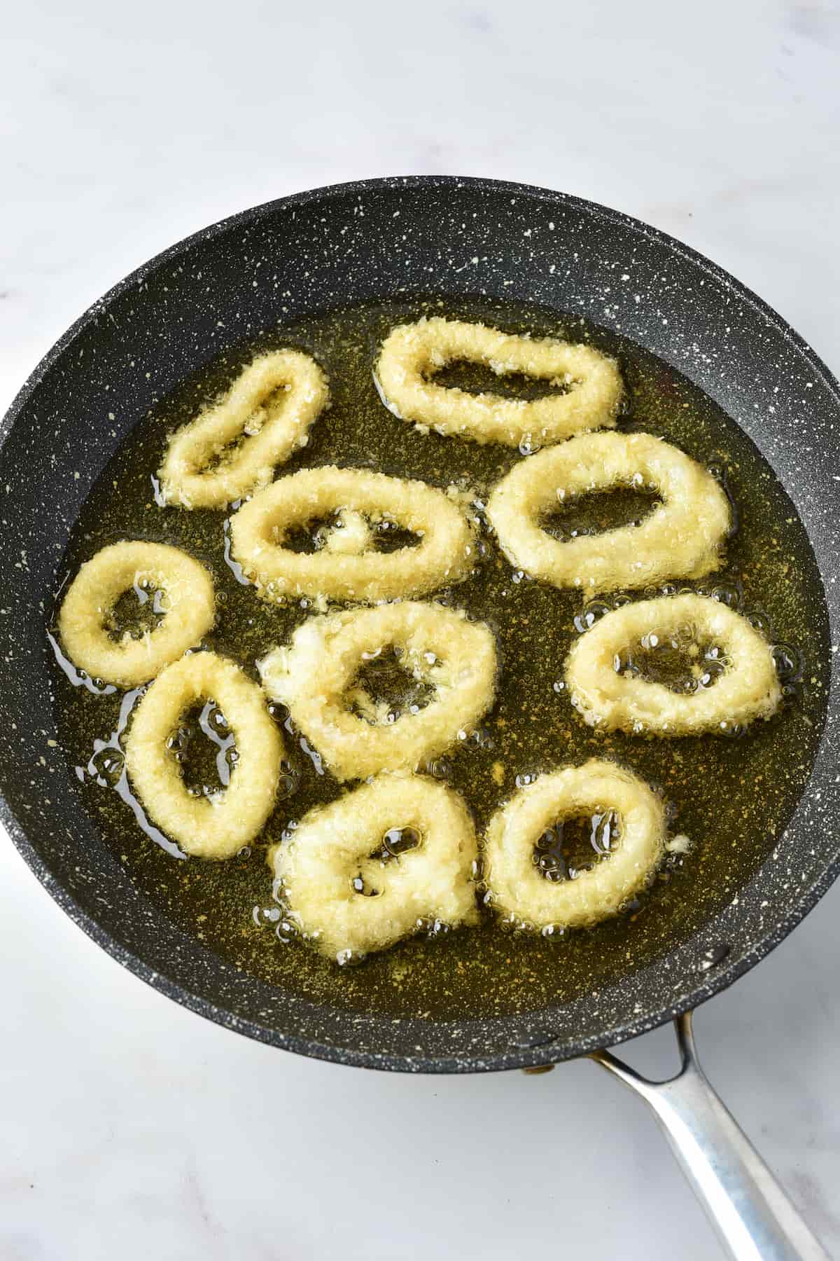 Calamari rings frying in a pan.