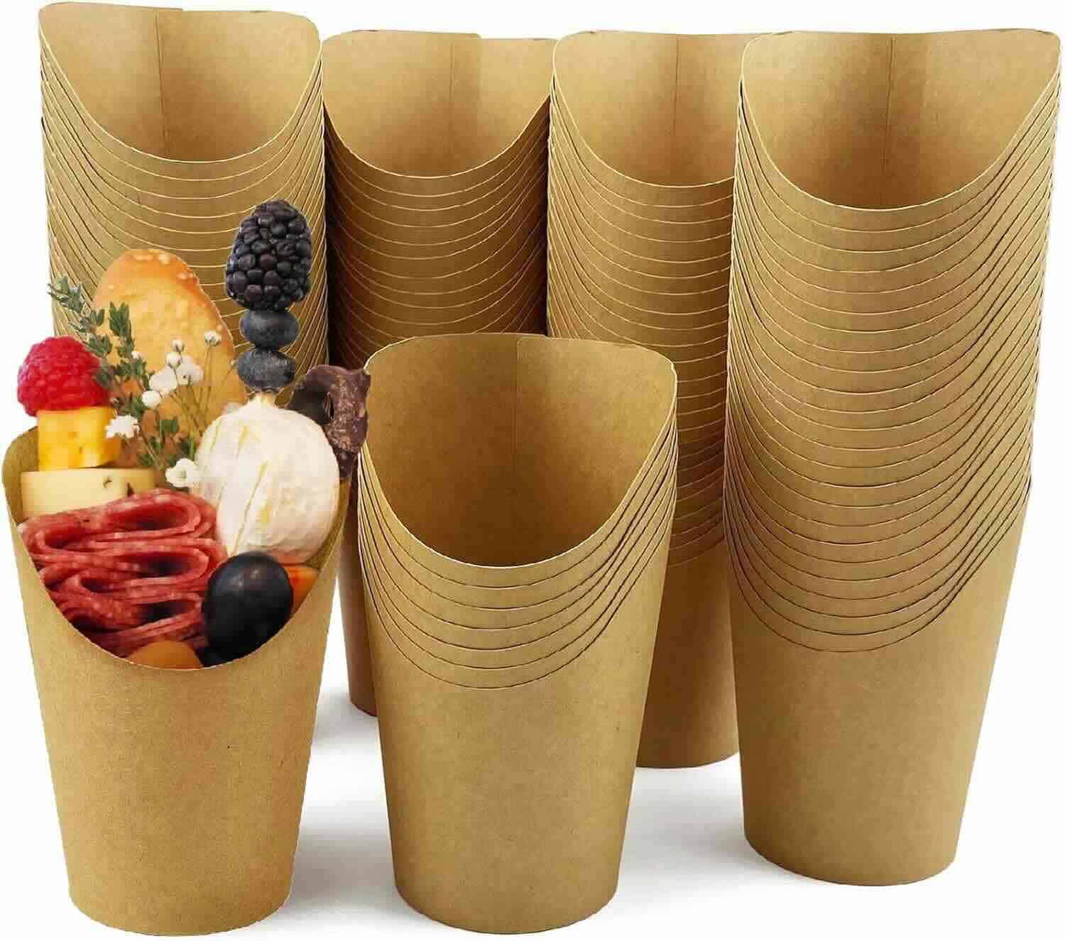 Stacked brown paper cups, with one cup in front filled with assorted charcuterie items including cheese, meats, fruits, and olives.