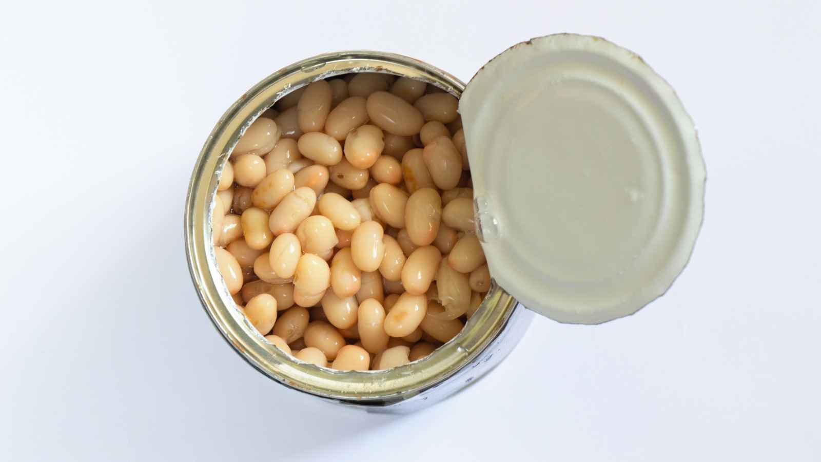 An opened can of white beans viewed from above, with the lid partially attached and beans visible inside.