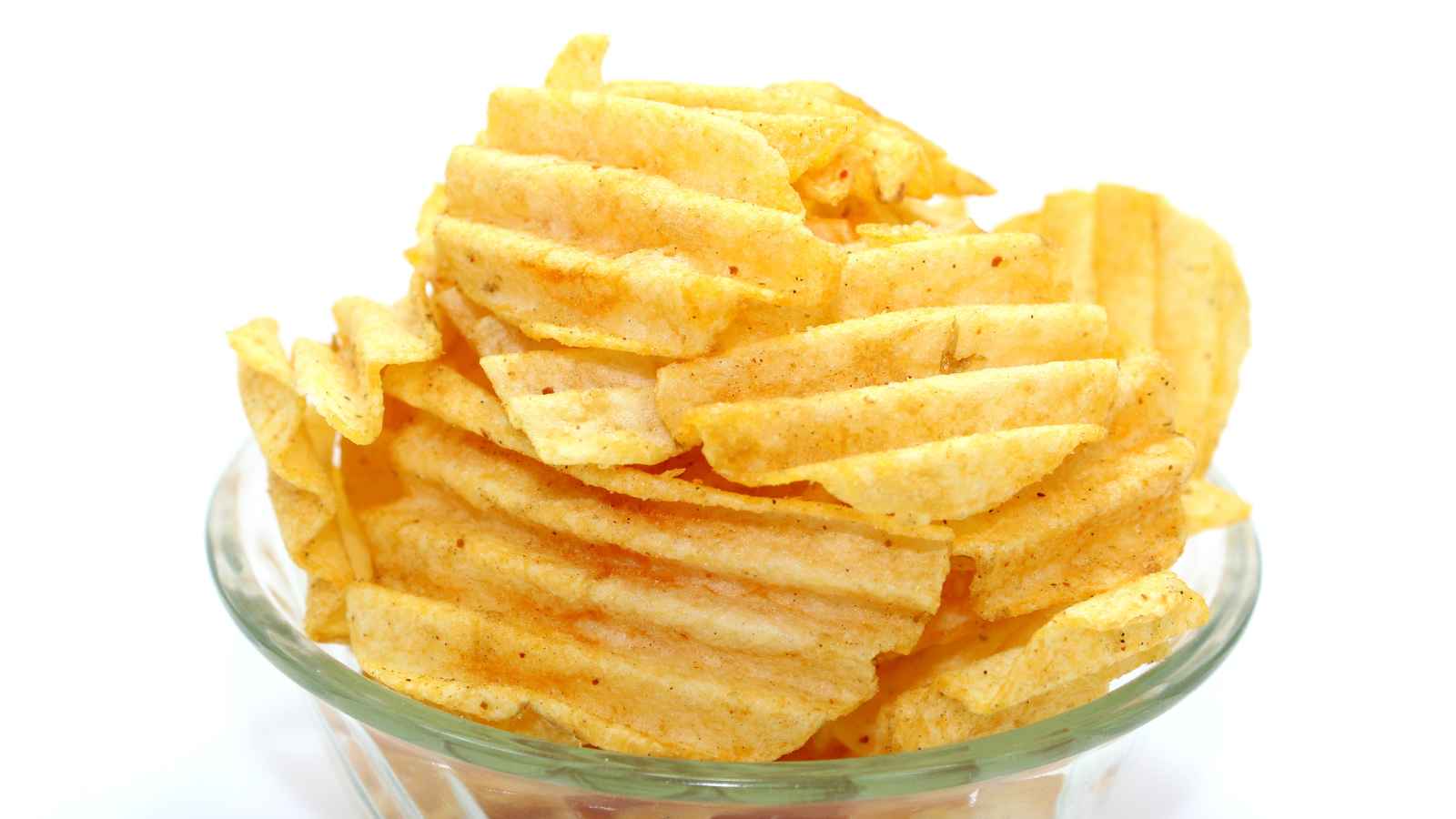 A clear glass bowl filled with ridged, seasoned potato chips against a white background.