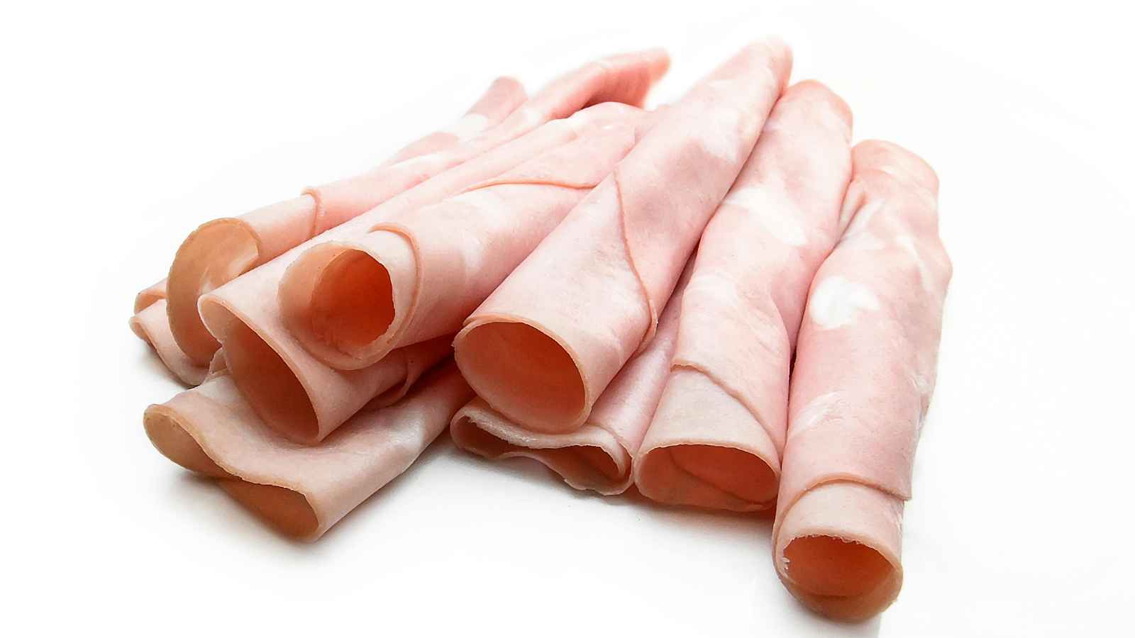 Several slices of rolled deli ham are arranged on a white background.