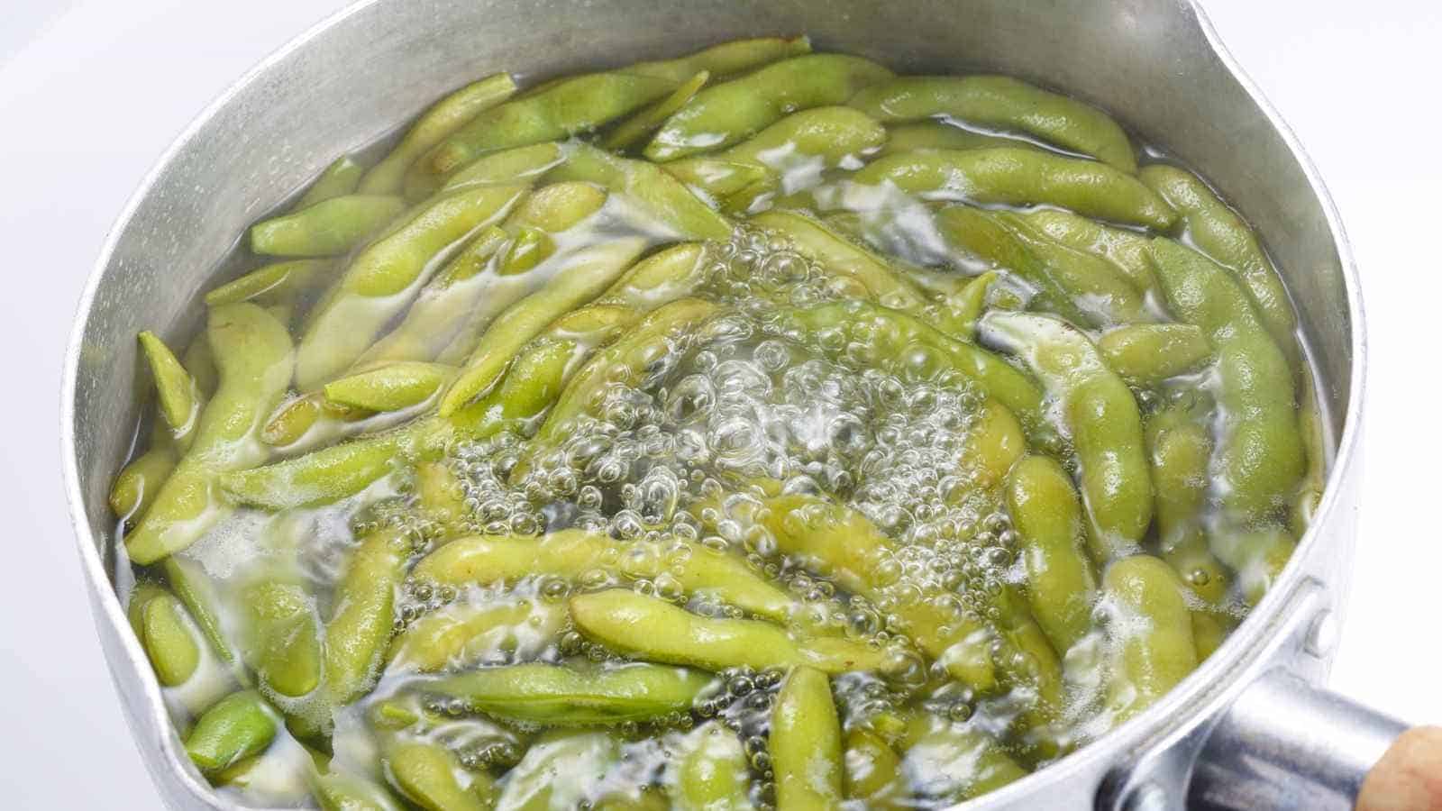 A pot of edamame pods boiling in water.