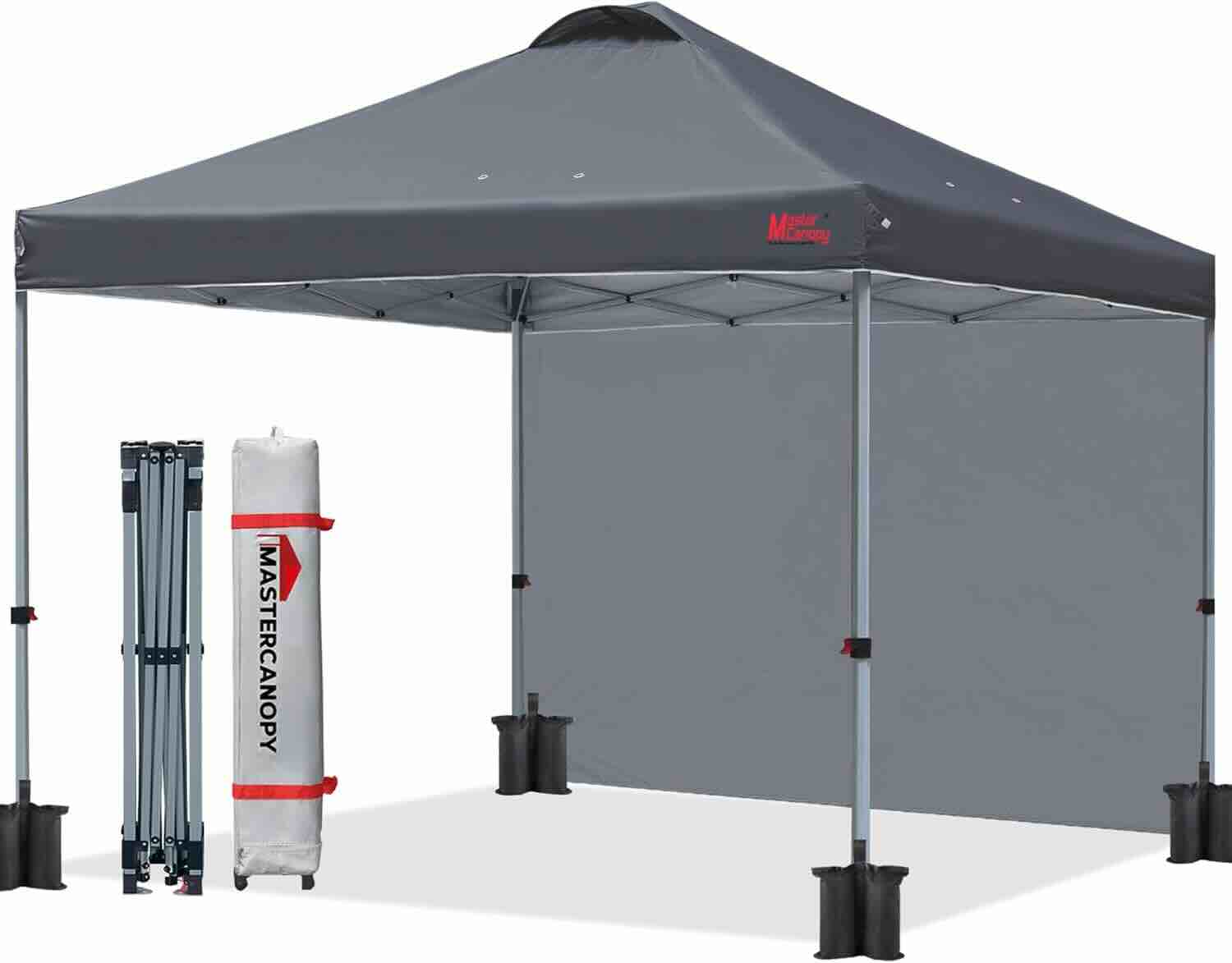 Gray pop-up canopy tent with sidewall, black leg weights, foldable metal frame, and a white carrying bag labeled “MASTERCANOPY.”.