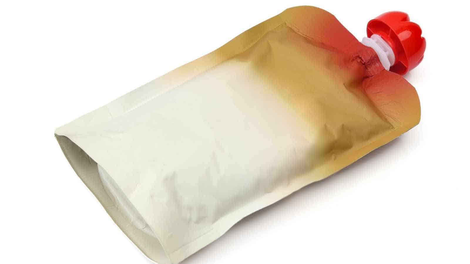 A sealed, metallic food pouch with a red plastic screw cap, lying on a white surface.
