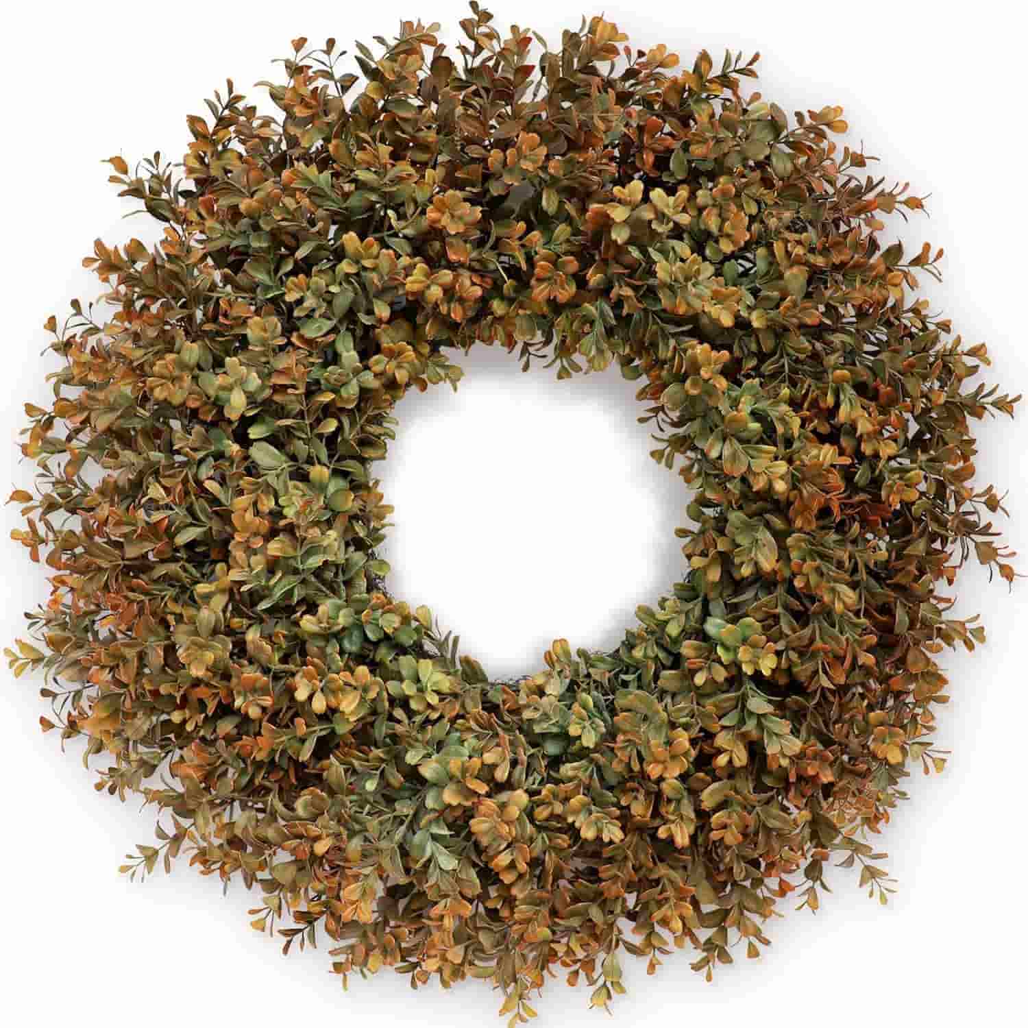 A circular wreath made of artificial boxwood leaves in varying shades of green and brown, arranged densely with an empty space in the center.