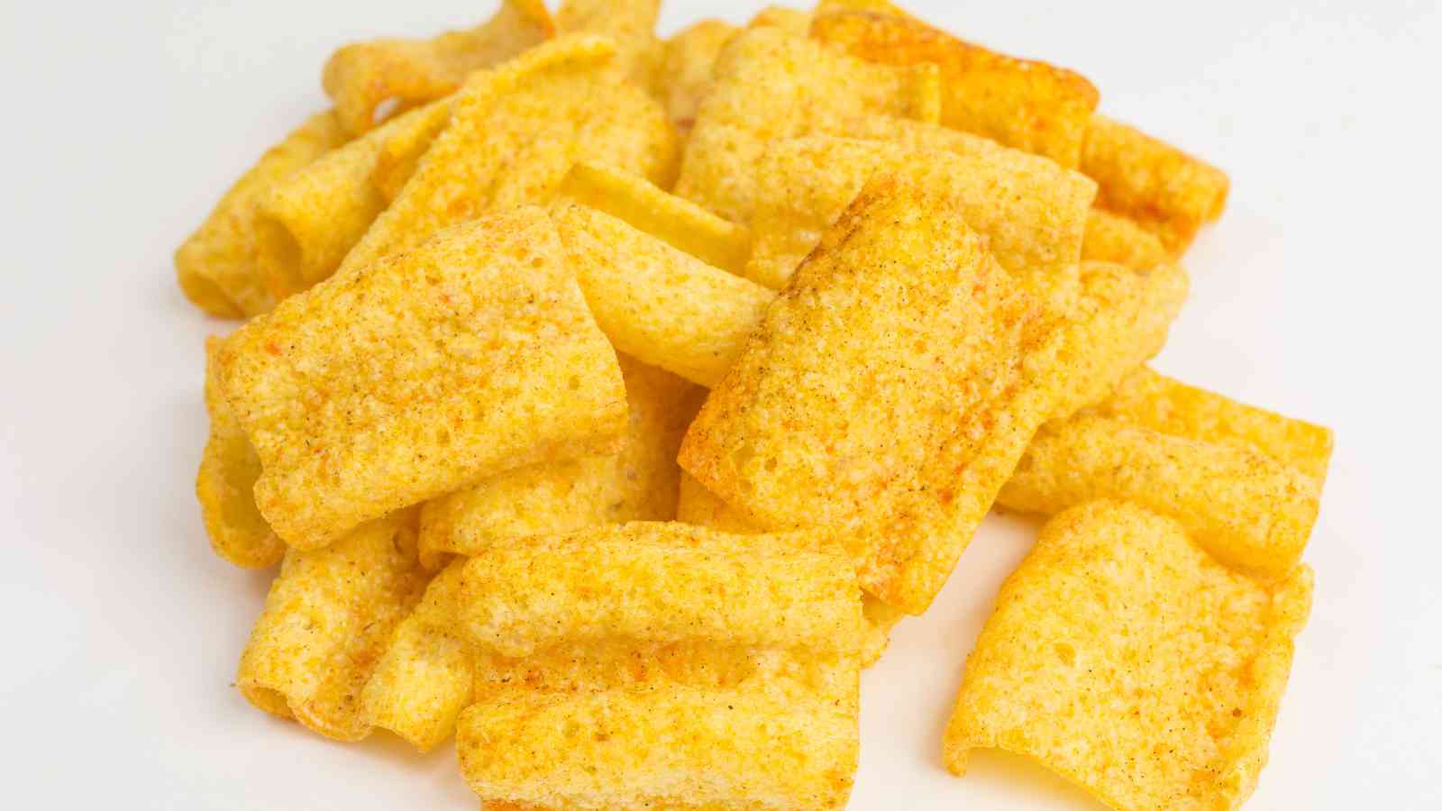 A pile of rectangular, yellow, crunchy corn chips with a light seasoning on a white surface.