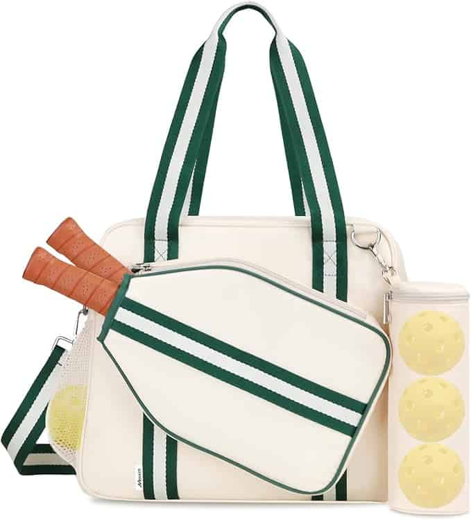 A cream-colored tote bag with green stripes, holding two pickleball paddles and a zippered case containing three yellow pickleballs.