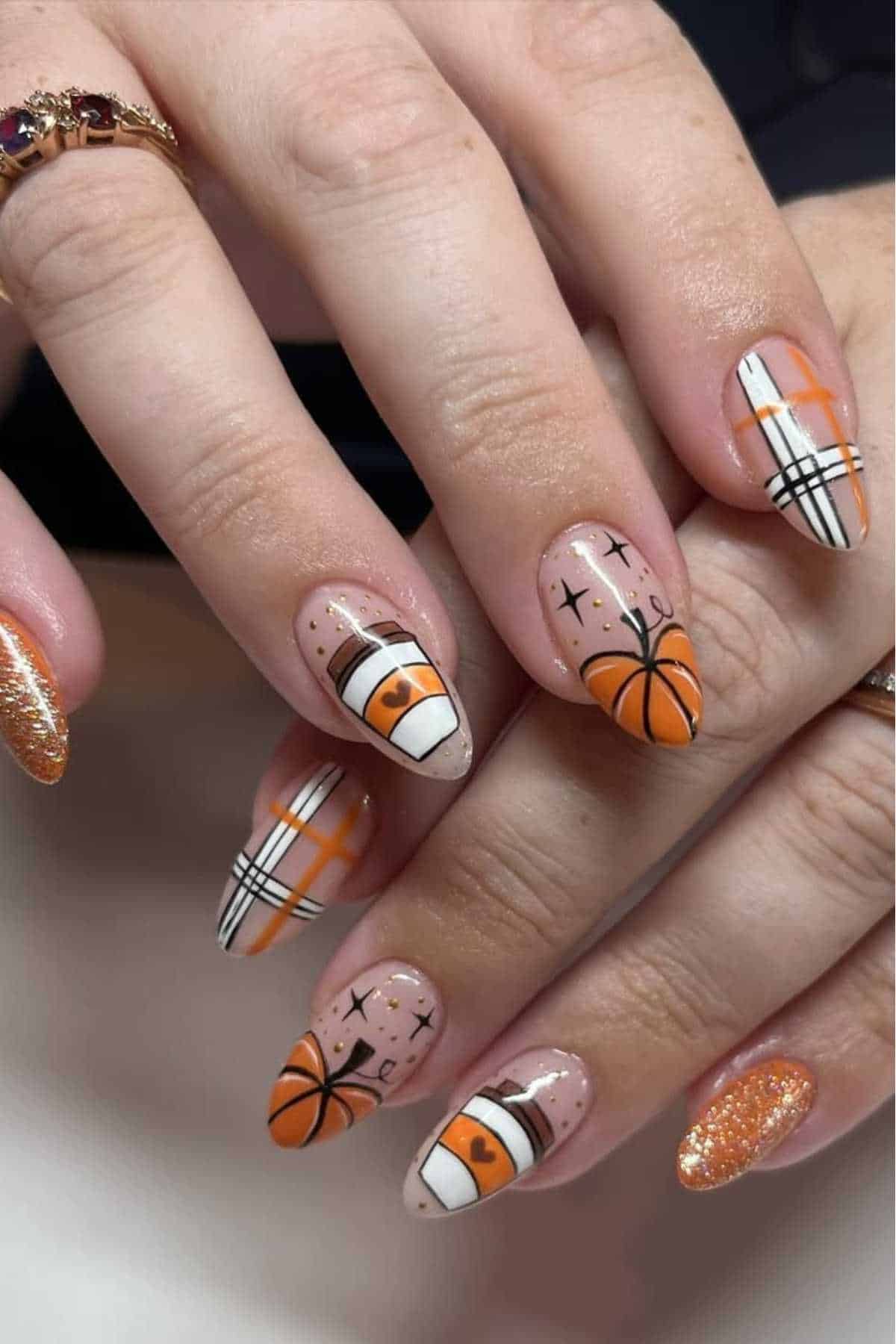 Fingernails with a Halloween-themed nail art, including images of pumpkins, checkered pattern, and orange glitter polish on some nails.