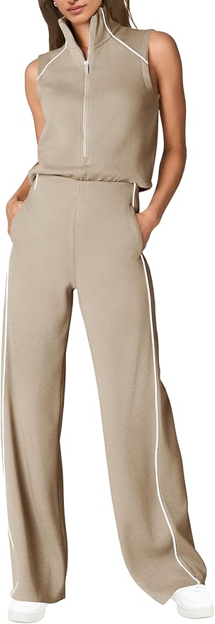A woman wearing a sleeveless beige zip-up top and matching wide-leg pants with white trim, and white sneakers, standing with hands in pockets.