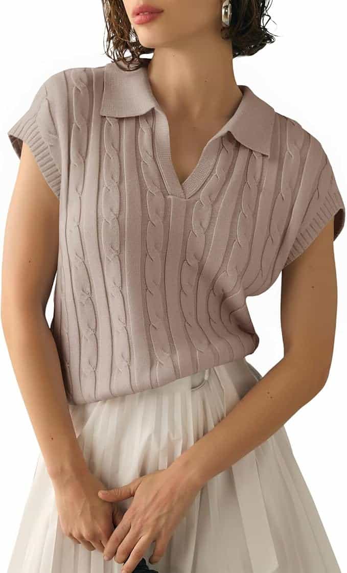 A woman wearing a light mauve short-sleeved cable knit sweater with a collar, paired with a white pleated skirt.