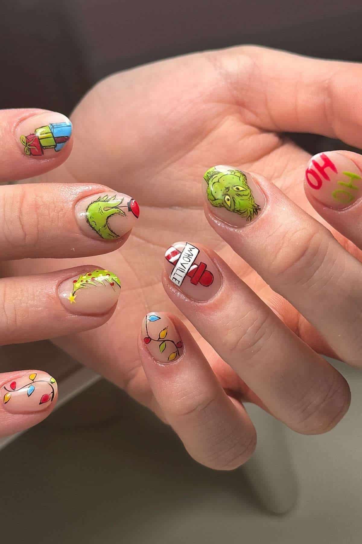 Fingernails with colorful Christmas-themed nail art, featuring the Grinch, holiday lights, presents, and festive phrases.