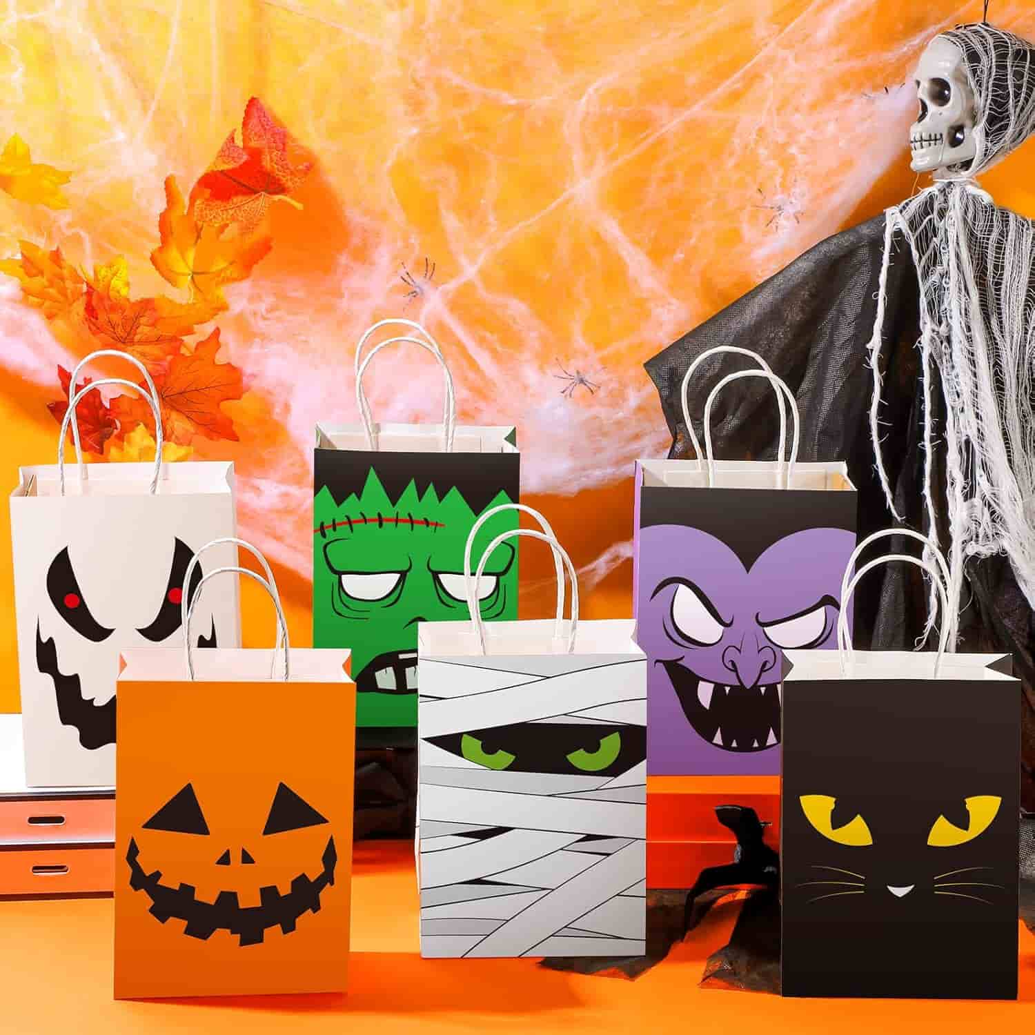 Five Halloween-themed gift bags with spooky faces are arranged on a table, with orange decorations and a skeleton figure in the background.