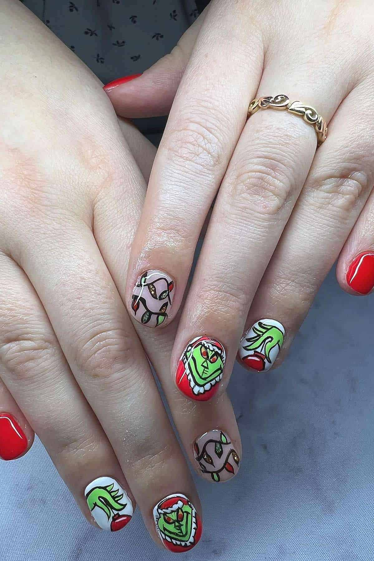 Close-up of hands with red nail polish and cartoon character designs, including faces with exaggerated expressions, on several fingernails.