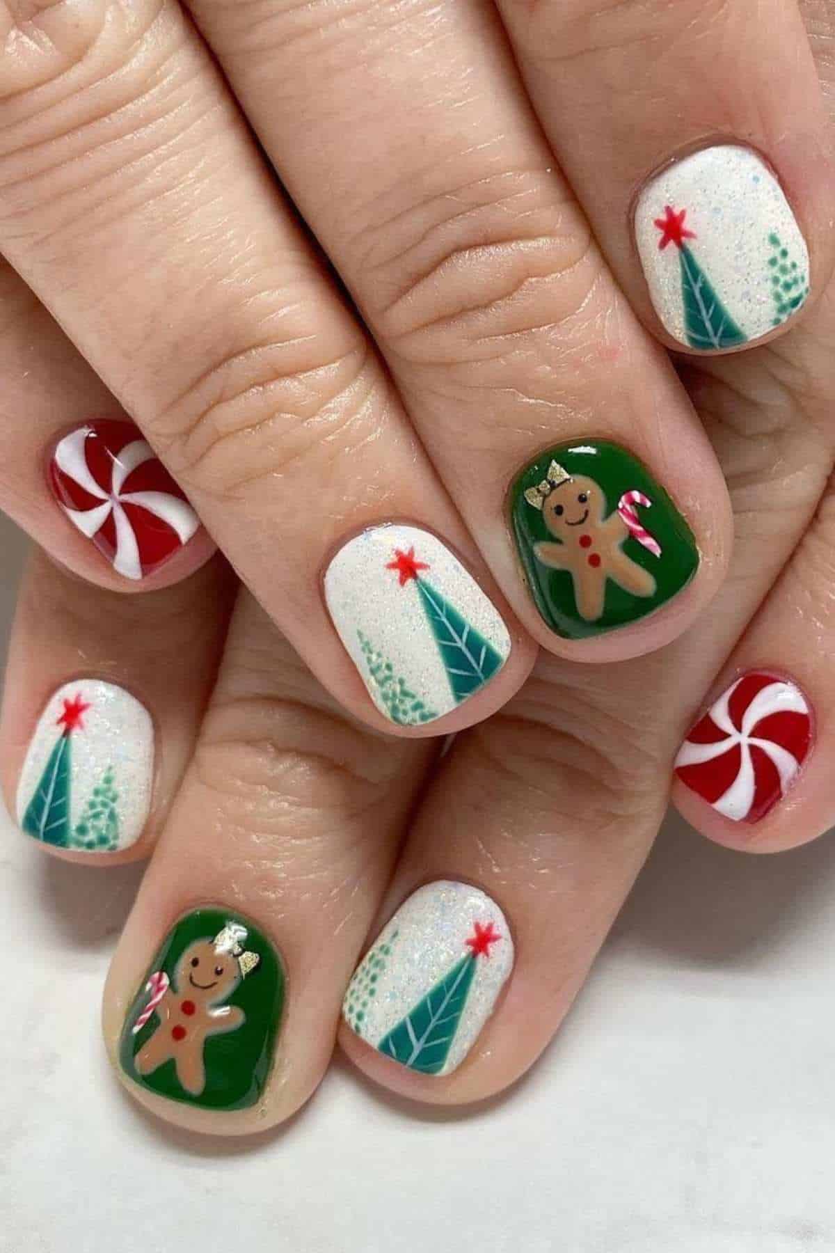 Fingernails painted with holiday designs including candy canes, Christmas trees, stars, and gingerbread men on a white and green background.