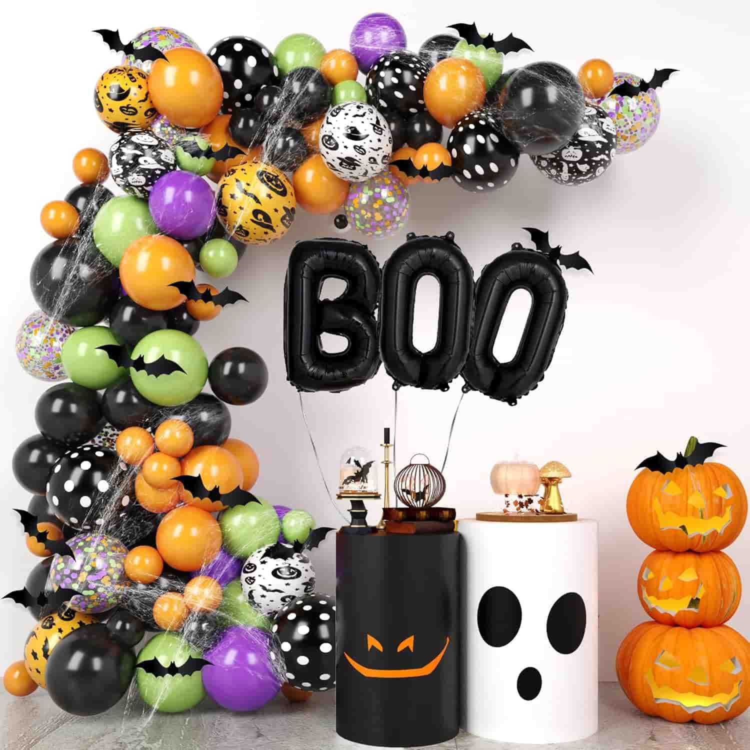 A Halloween party setup with orange, black, green, and white balloons, "BOO" letter balloons, pumpkin and ghost decorations, and stacked jack-o'-lanterns.