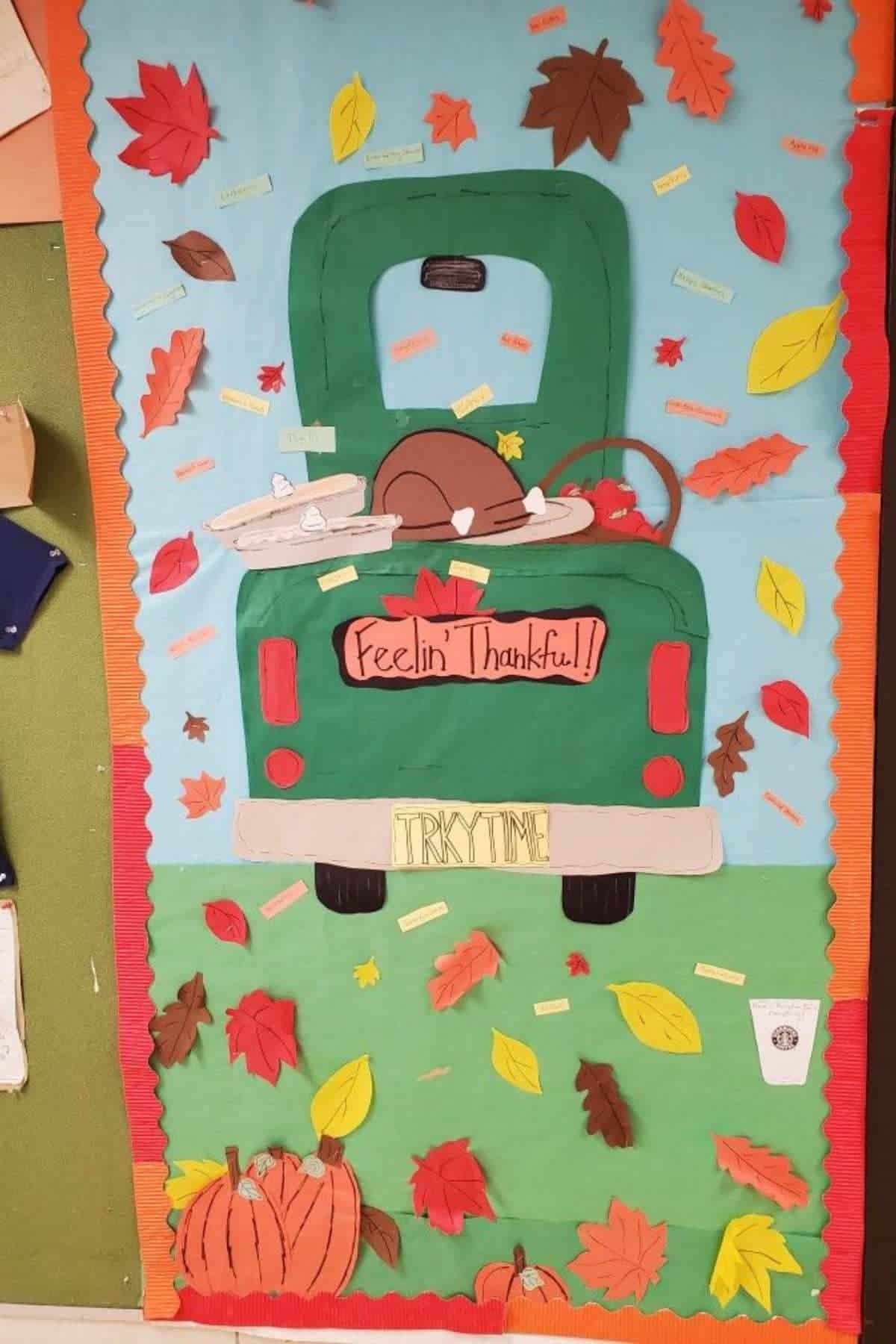 A decorated bulletin board features a green truck loaded with Thanksgiving food, fall leaves, and pumpkins. The truck's sign reads "Feelin' Thankful!" and the license plate says "TRKYTIME.