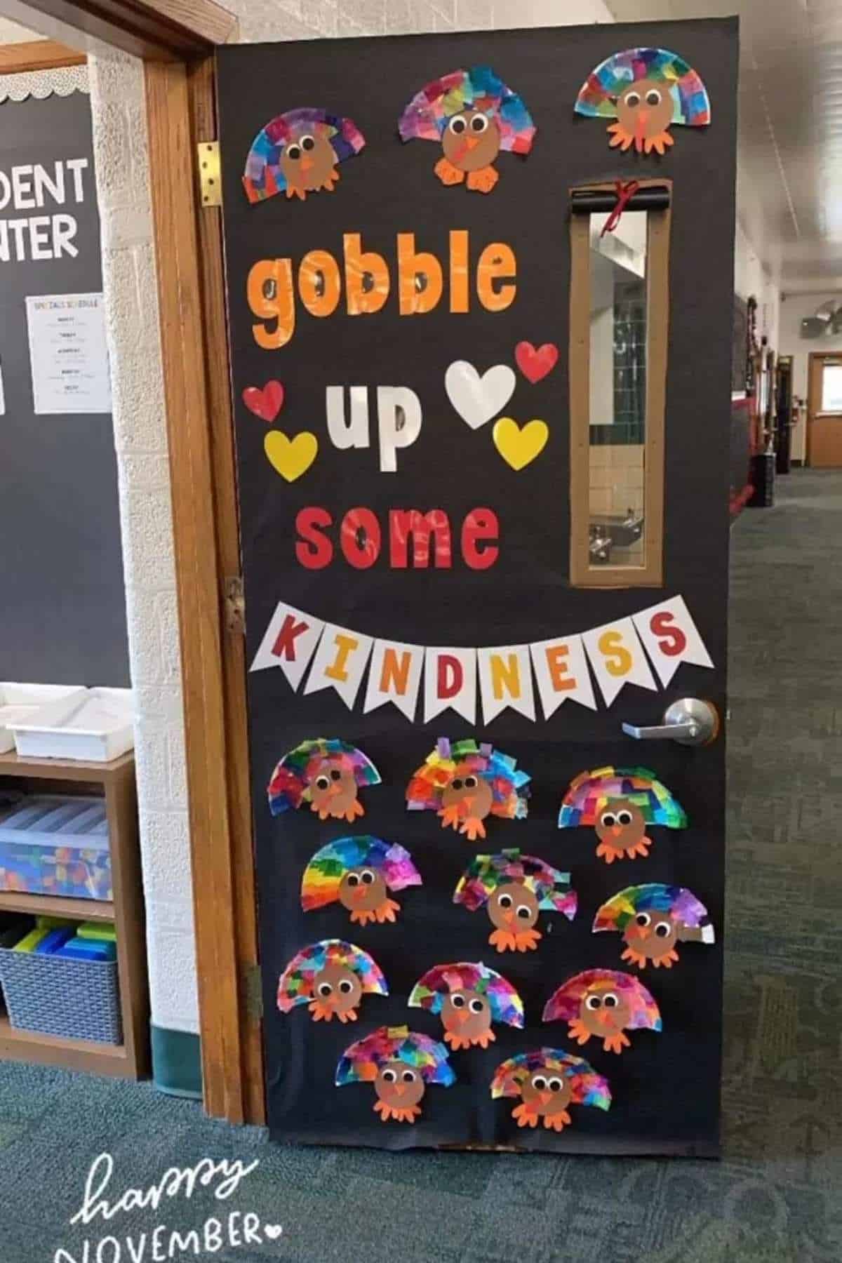 A classroom door decorated with the phrase "gobble up some kindness," colorful paper turkeys, and hearts, celebrating November and the Thanksgiving season.