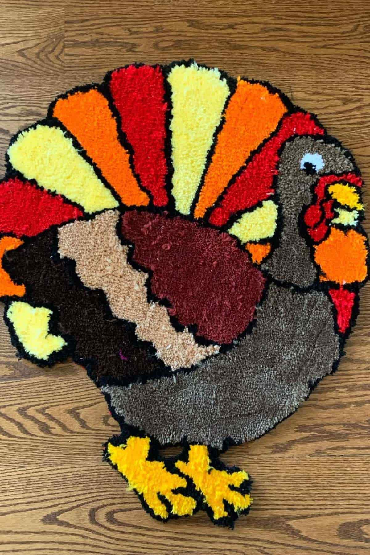 A colorful, turkey-shaped rug with orange, yellow, red, and brown sections, placed on a wooden floor.