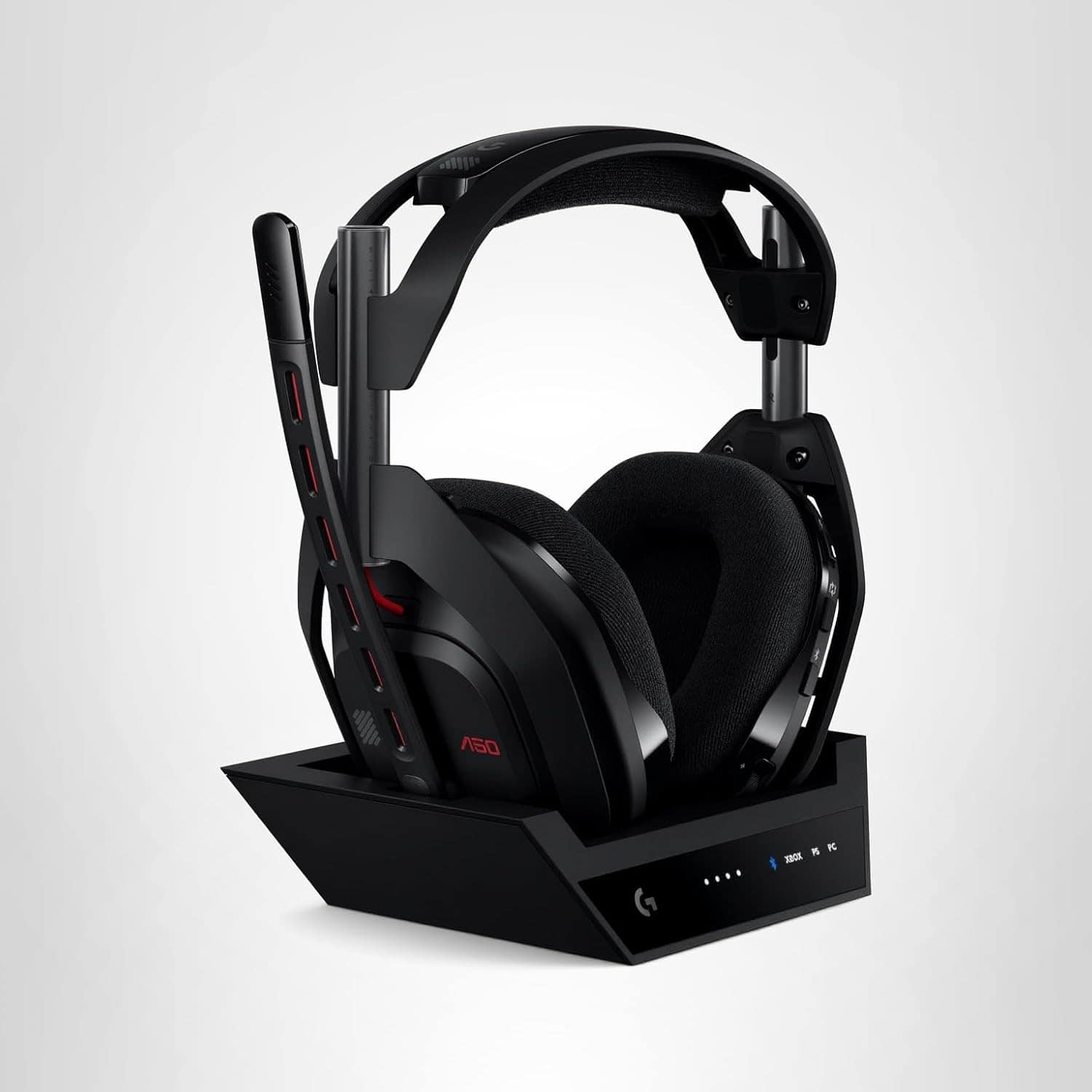 A black wireless gaming headset with a microphone is placed on a charging dock against a plain white background.