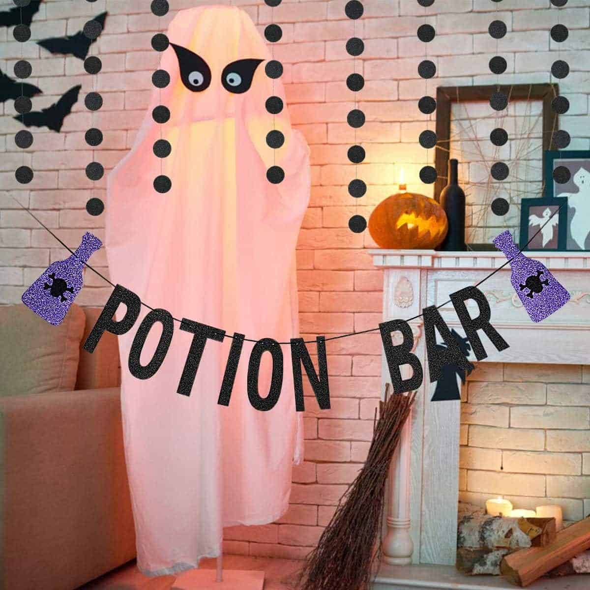 A ghost decoration stands by a fireplace with Halloween decor, including a "Potion Bar" banner, candles, a pumpkin, and hanging dot garlands.