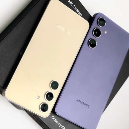 Two Samsung Galaxy S23 smartphones, one gold and one purple, are placed side by side on Galaxy S23-branded boxes.