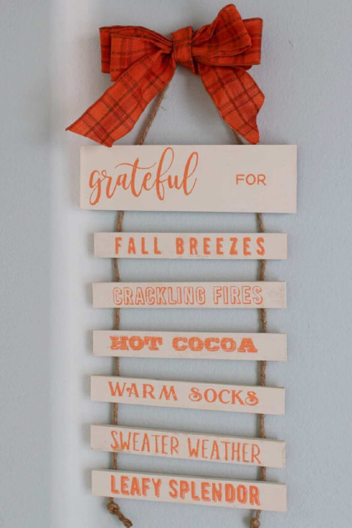 A decorative hanging sign with an orange plaid bow reads "grateful for" and lists fall breezes, crackling fires, hot cocoa, warm socks, sweater weather, and leafy splendor.