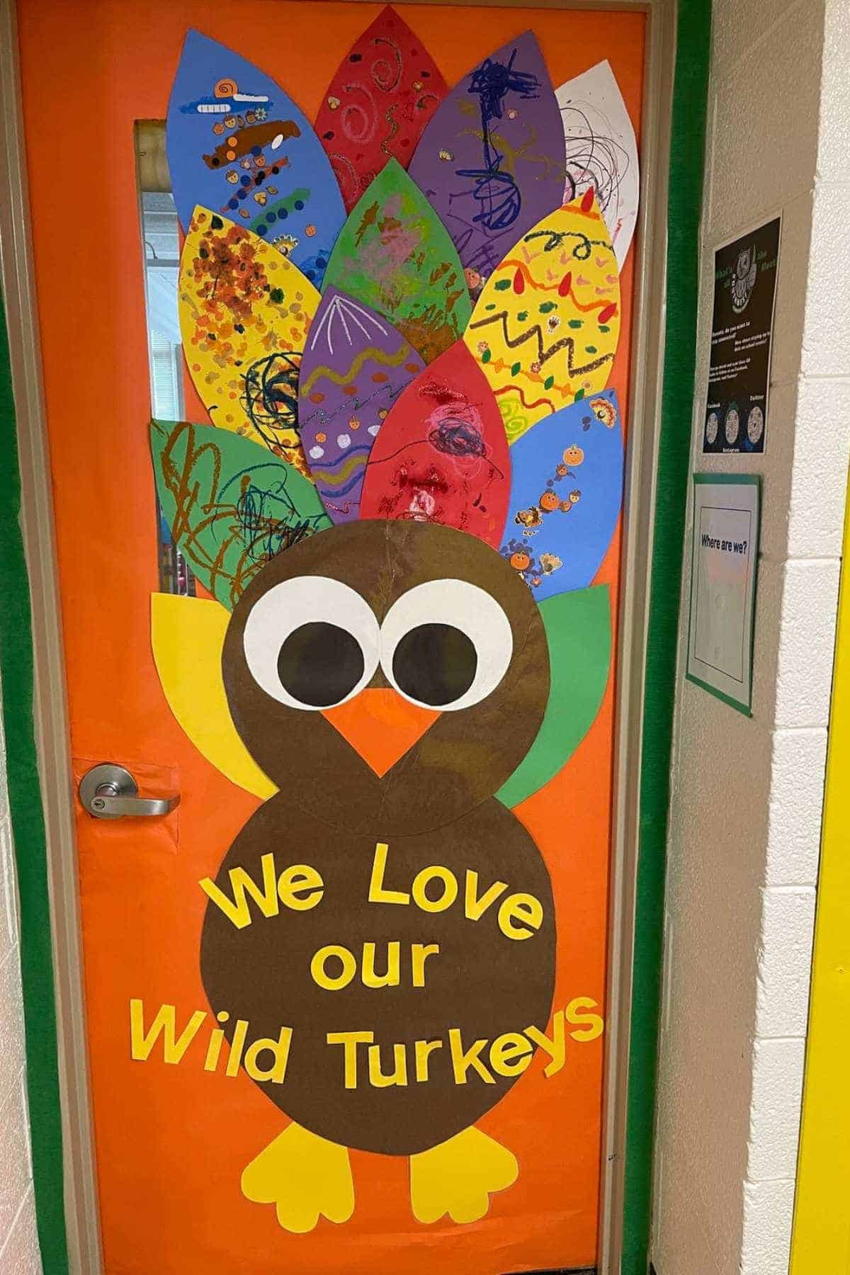 A classroom door decorated with a large paper turkey and colorful feathers. The sign on the turkey reads "We Love our Wild Turkeys.