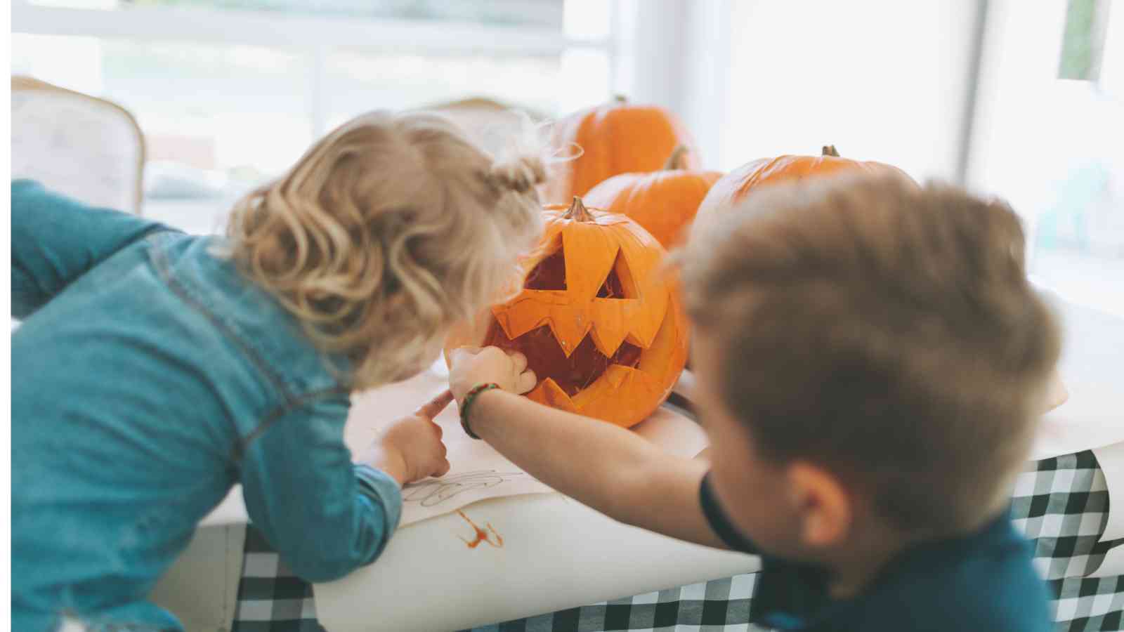 A boy and girl painting a jack-o-lantern.