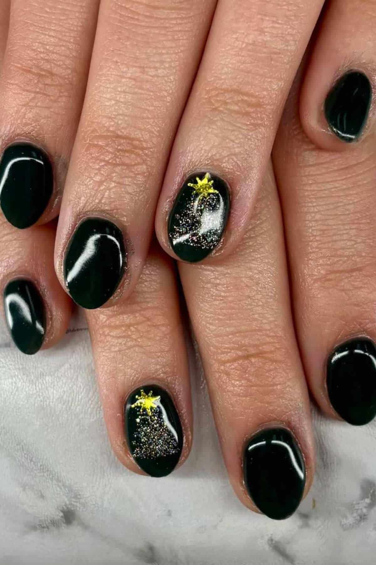 Fingernails painted dark green with one accent nail on each hand featuring a yellow star and silver glitter design.