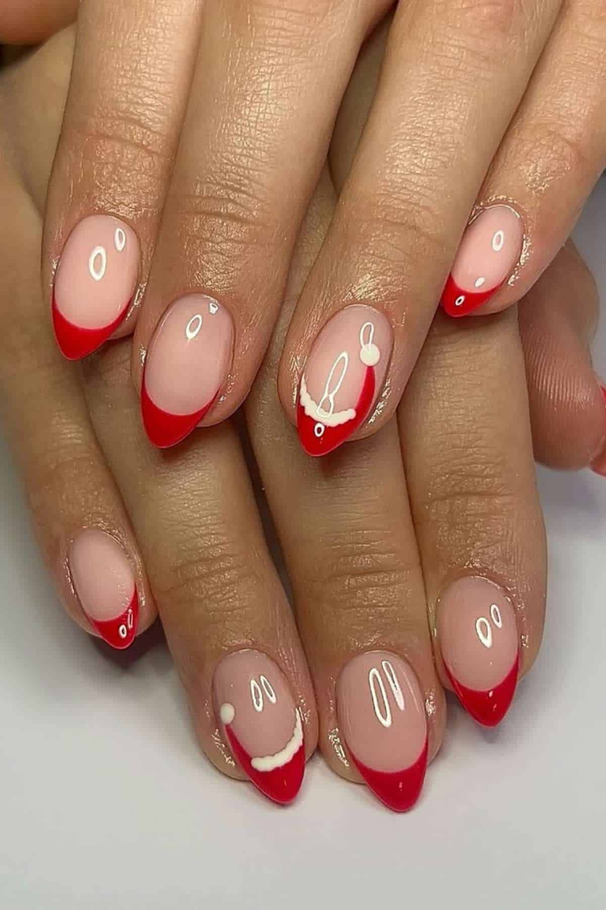 Hands with almond-shaped nails featuring red French tips and playful white smiley face designs on a nude base.